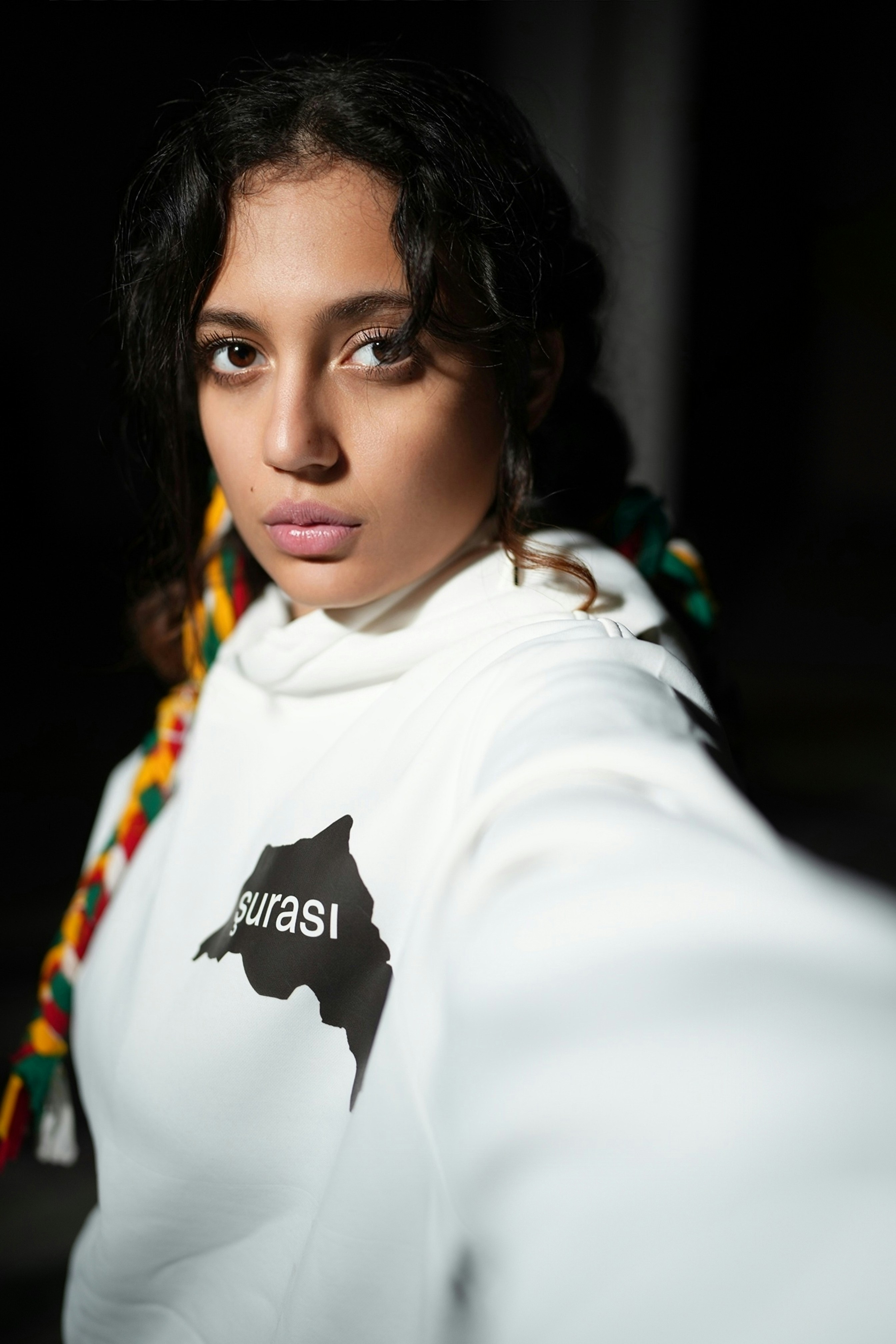 A young woman with curly hair wearing a white hoodie.