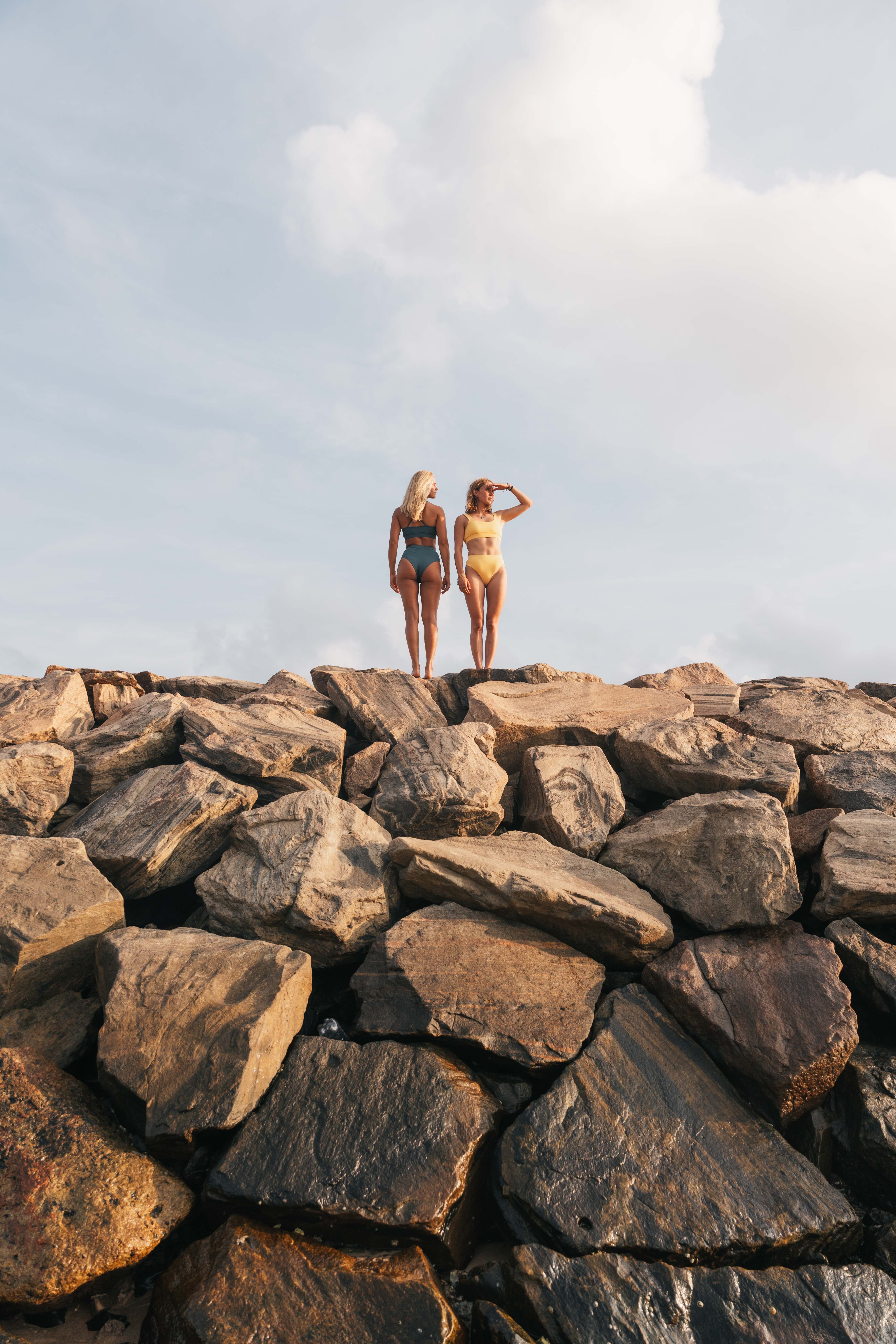 Two girls standing on a lot of gray rocks 