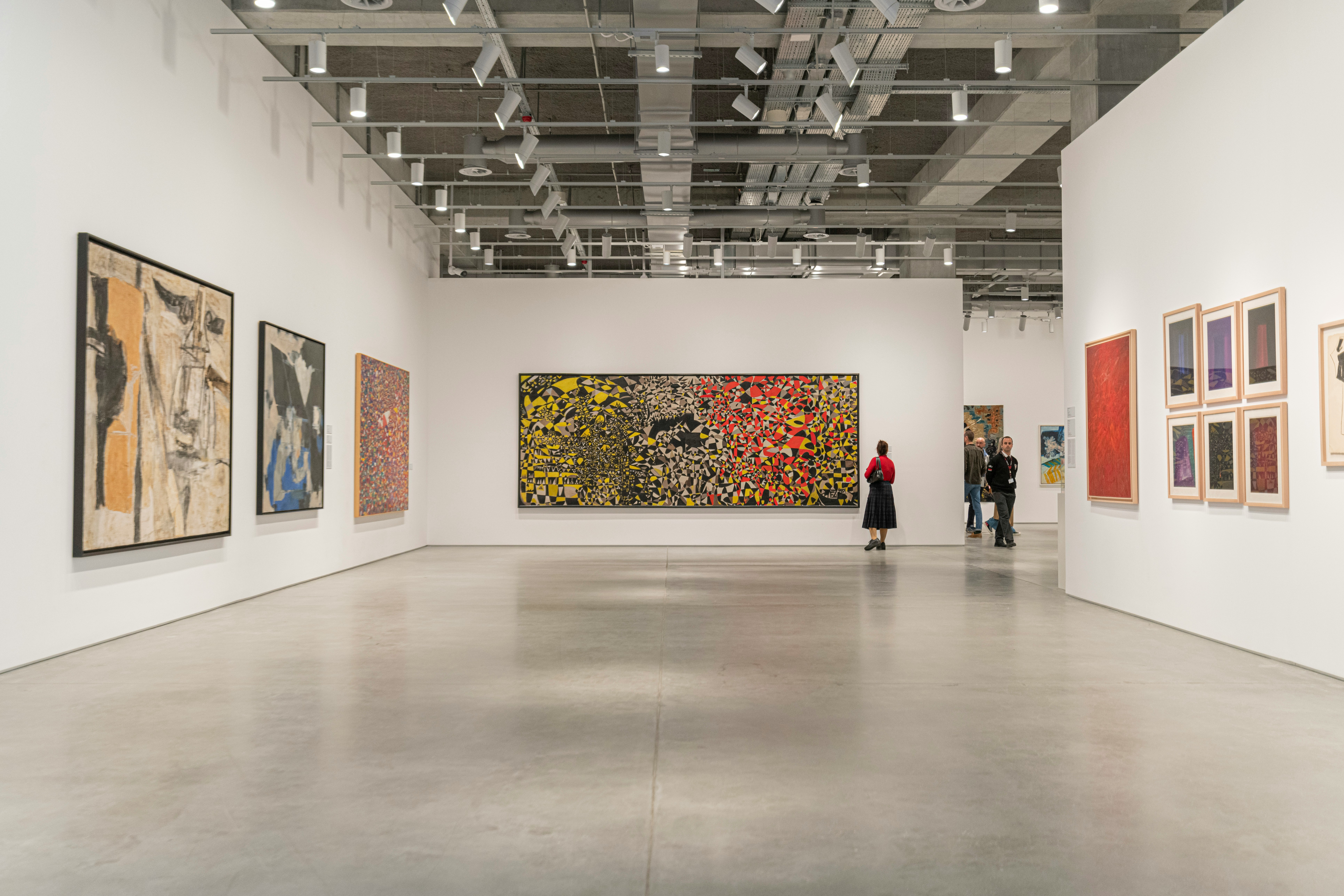 a woman looking at paintings on a wall