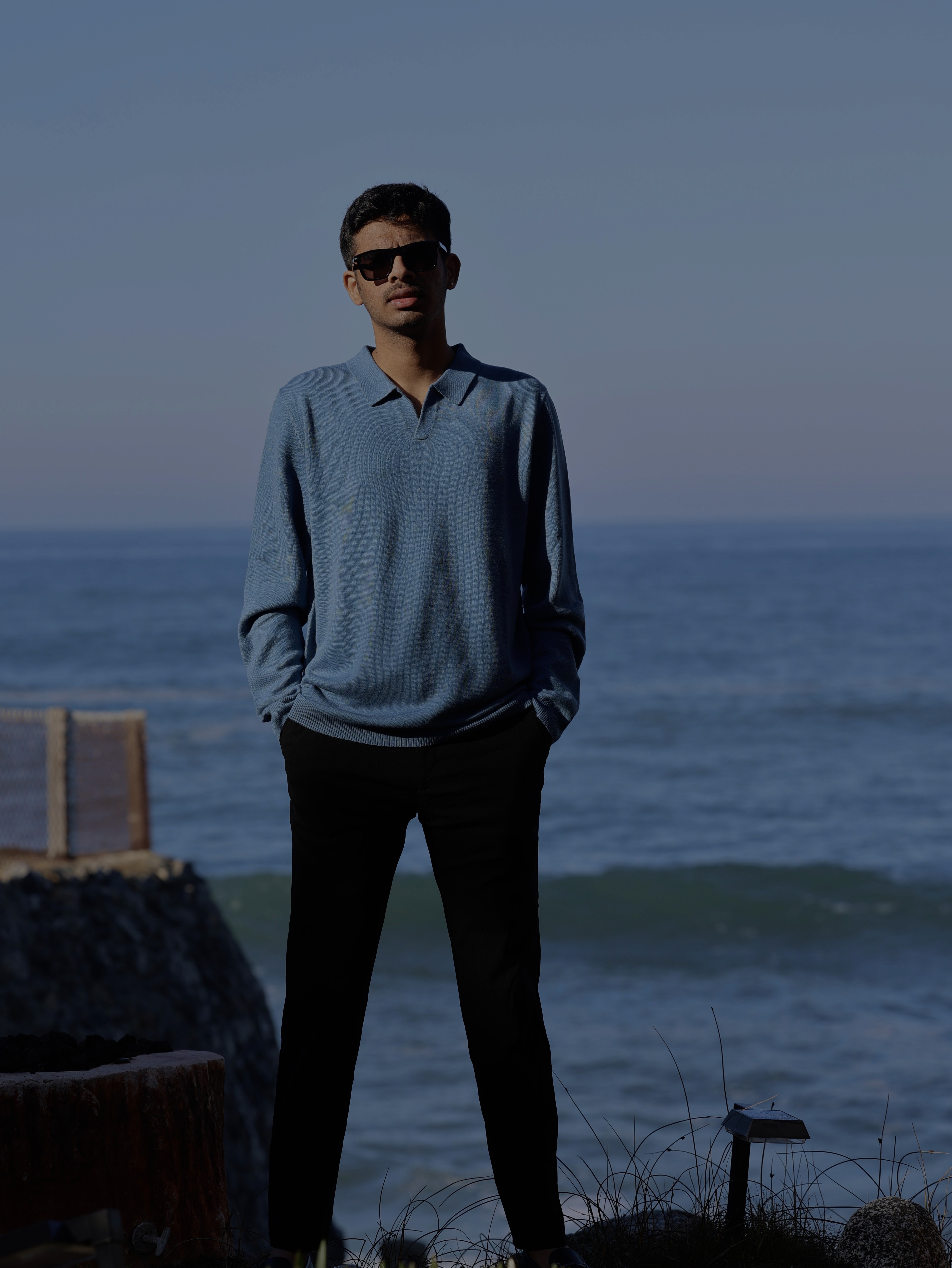 Smiling female therapist with short gray hair, wearing a brown top and a purple shawl, surrounded by a cozy background.
