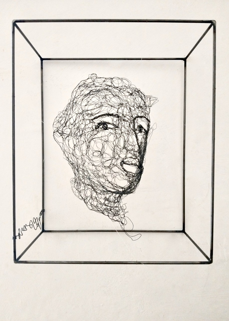 Sculpture en fil de fer représentant le visage d'une femme dans un cadre en fil de fer, vue détaillée de face