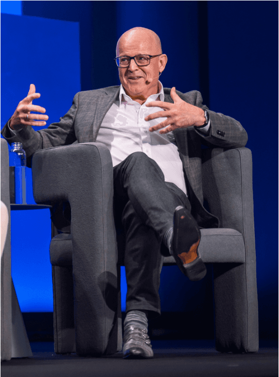 Peter Adriaens sits in a chair, wearing a suit