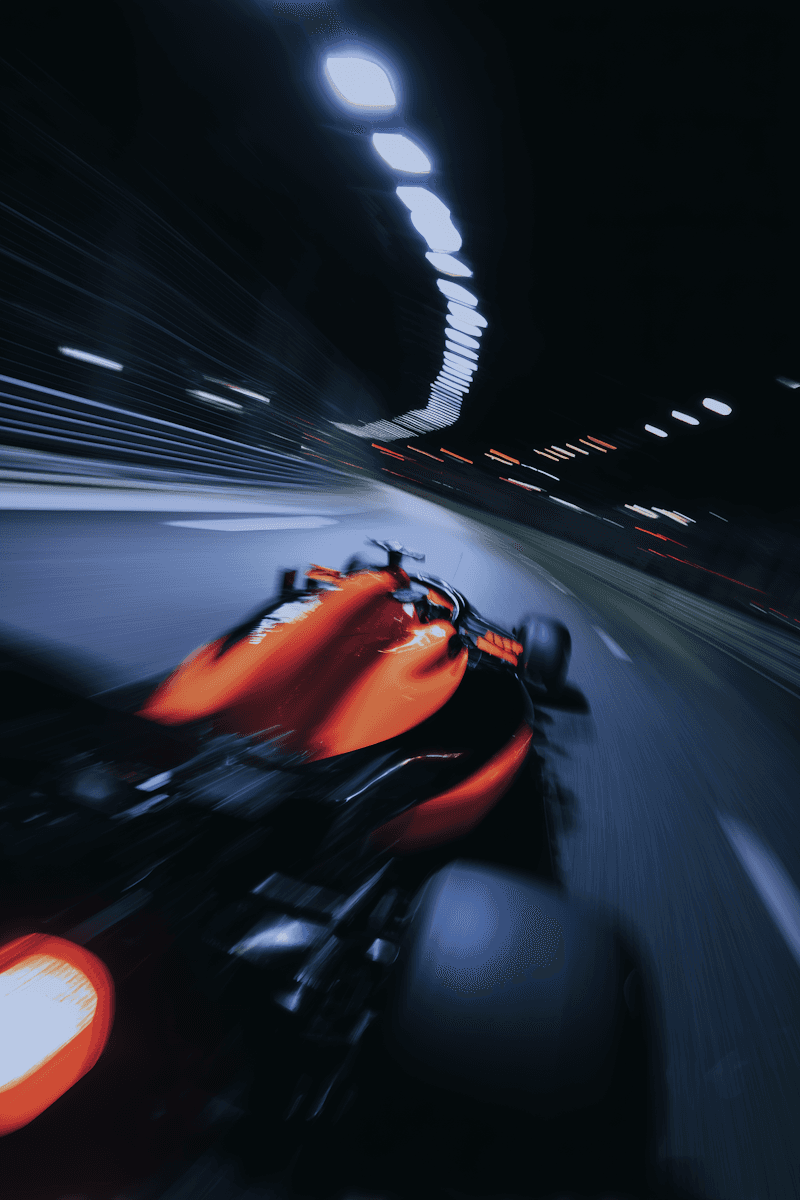 A dynamic shot of a racing car speeding through a tunnel, illuminated by bright overhead lights.