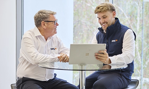 Rooftop garden with trees and plants, overlooking a cityscape at sunset with a tall building in the background