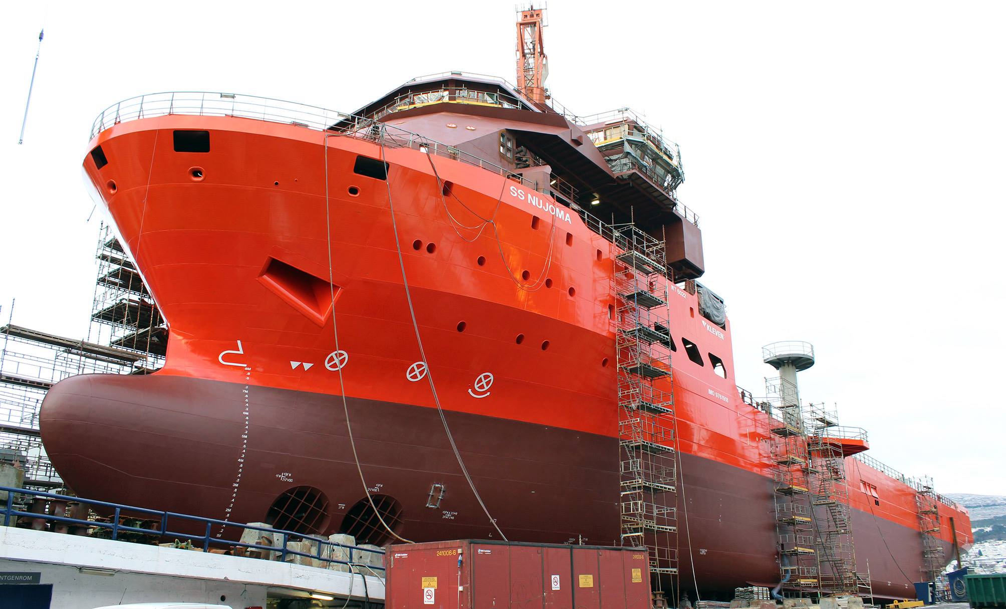 An orange ship docked at a pier, showcasing its large structure and industrial design.
