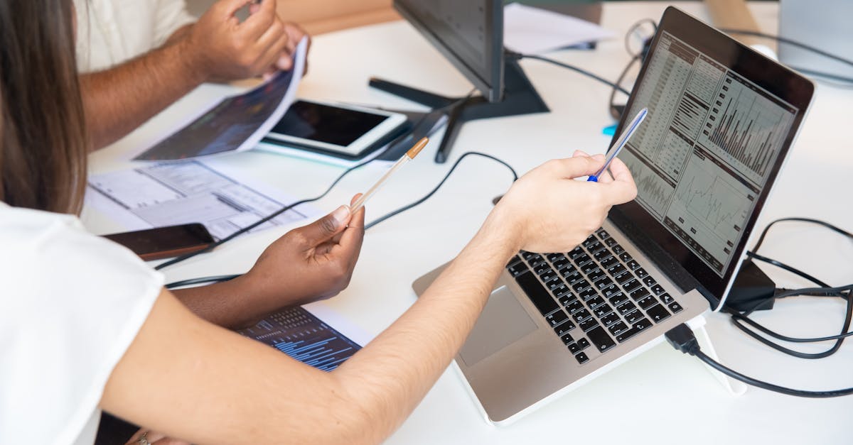 Professionals analyzing data charts on a laptop in an office setting, collaboratively discussing ins