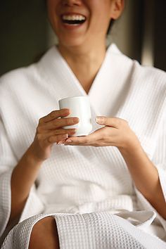 A woman lying down with a towel wrapped around her head, her face glowing with facial oil. She has a peaceful expression, enjoying a skincare treatment.