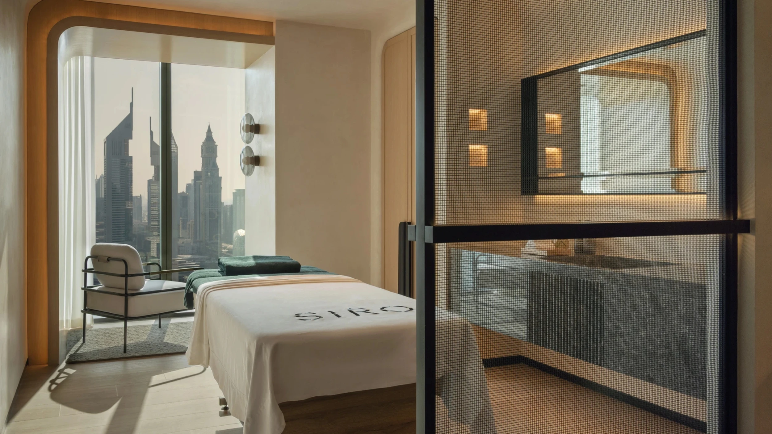 Recovery treatment room with a massage table, large window views, and a glass-partitioned spa area