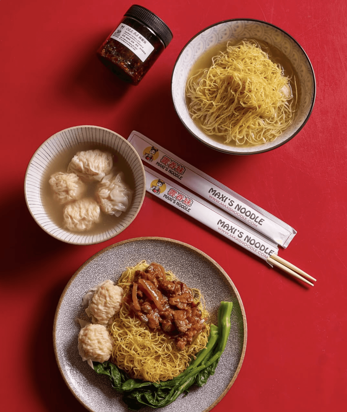 A plate of chewy lo mein noodles paired with a side of steaming broth, showcasing the traditional mix-and-sip dining style of Hong Kong cuisine.