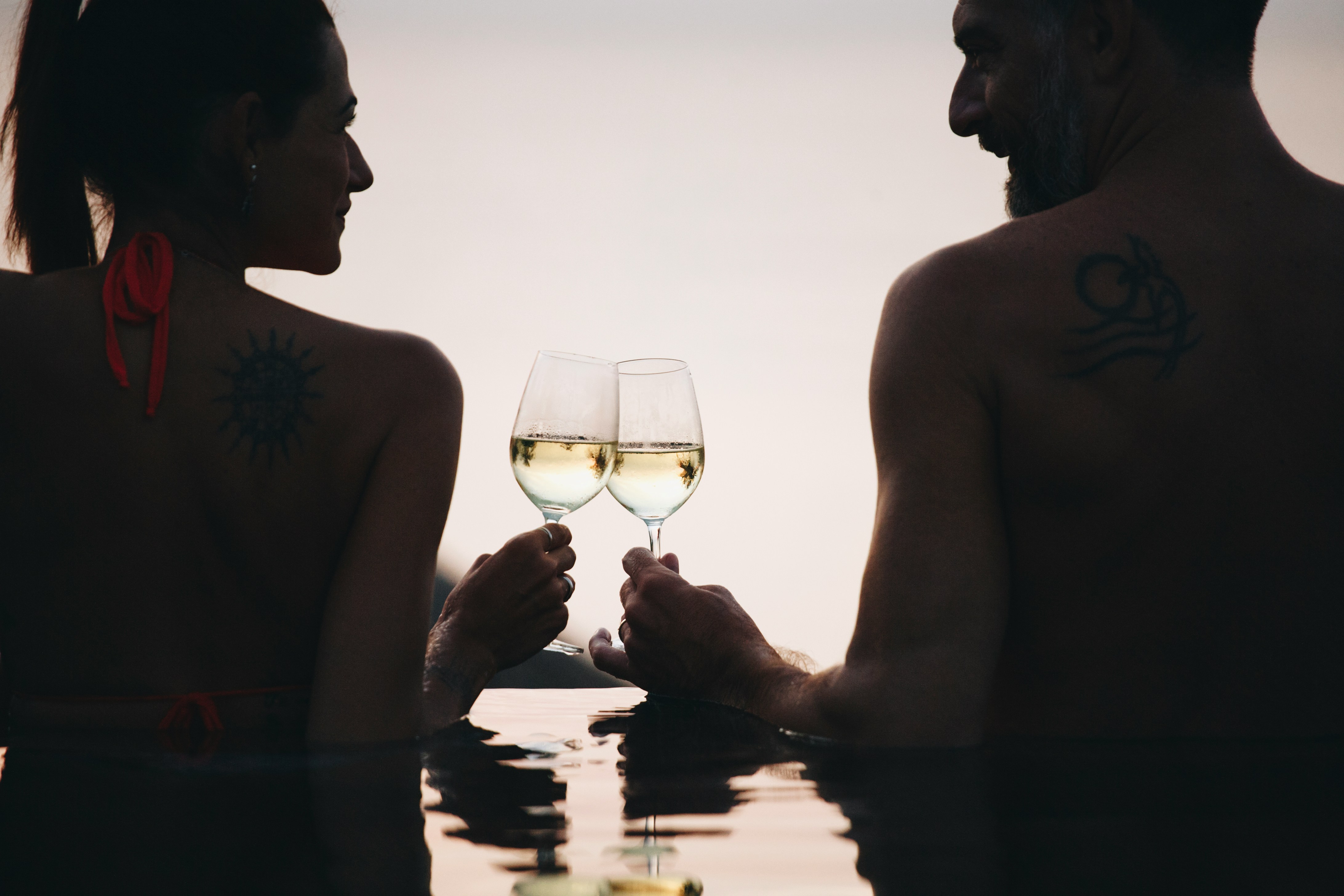 Couple holding glasses of wine while relaxing in a geothermal hot tub.
