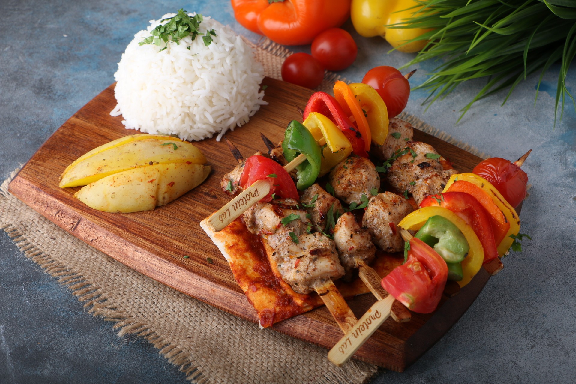 An overhead shot of a large oval plate featuring sliced, roasted duck, half glazed with a sauce, served over two thin pancakes and alongside steamed bok choy, surrounded by small bowls of condiments like scallions, sauce, salt, and carrot shreds.