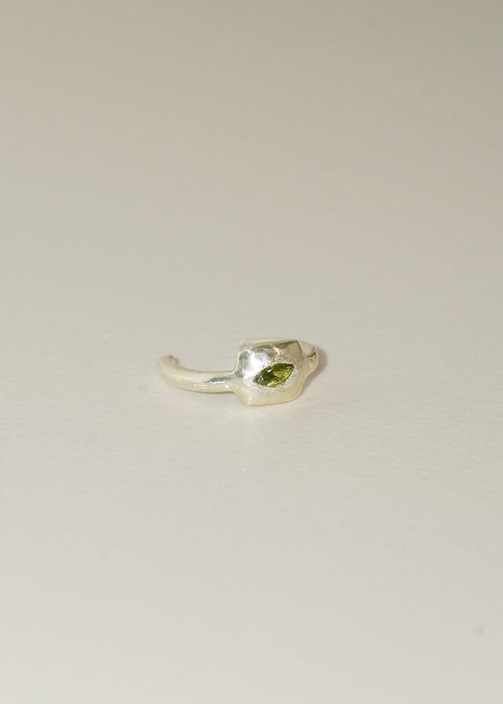 Silver ring with a green gemstone on a light beige background