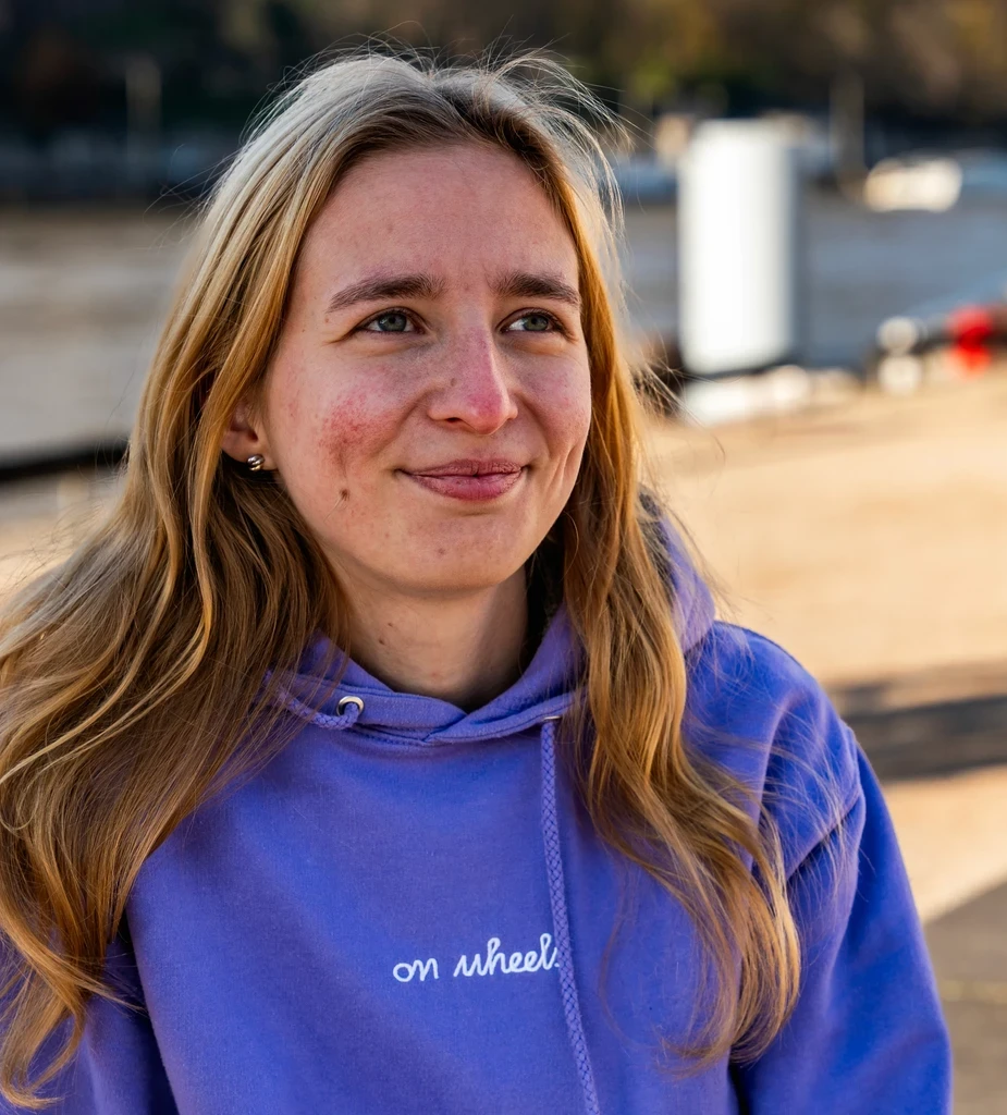 Camille ZWICK, cofondatrice de On Wheels, portant un hoodie violet et souriant en extérieur