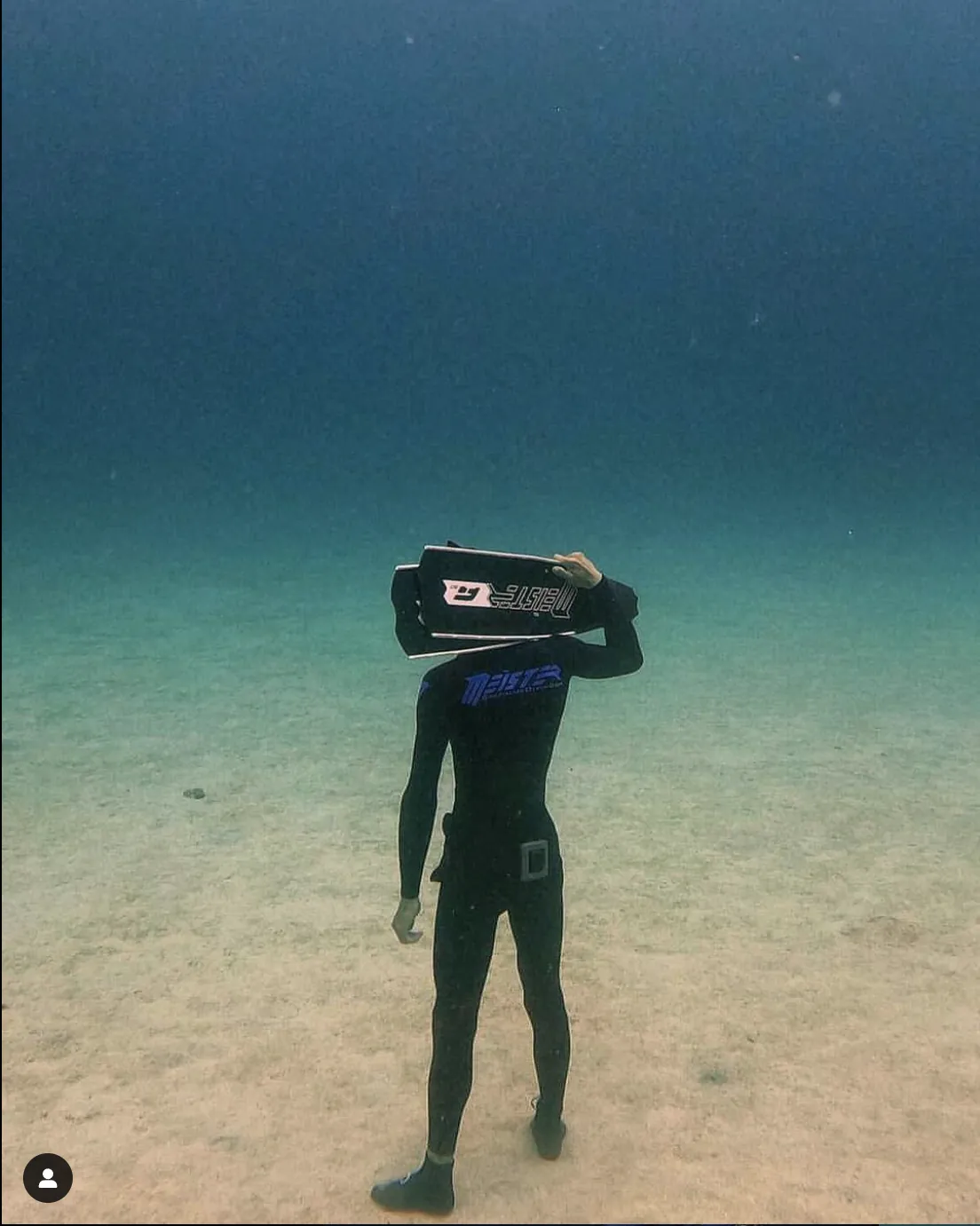 freediver meister holding fins standing underwater