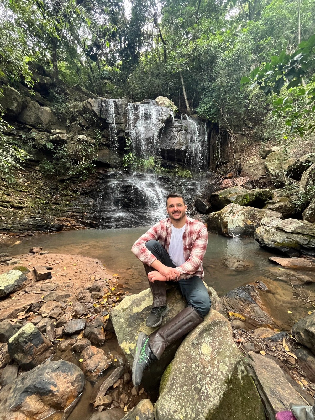 Sandro, founder of Pantanal Spirit Tours, sitting in front of a waterfall in the Serra das Araras – a symbol of new paths in sustainable tourism.