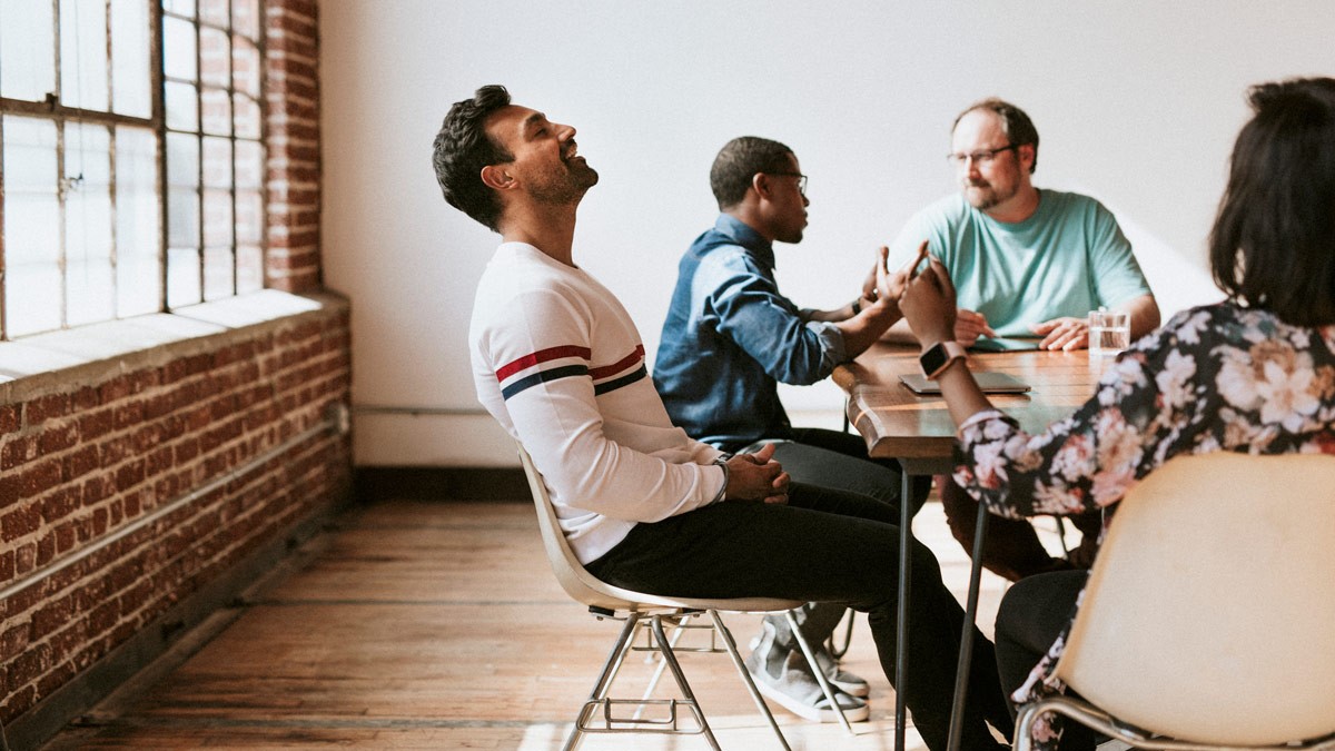 A group of workshop participants sitting around a table and having a conversation.