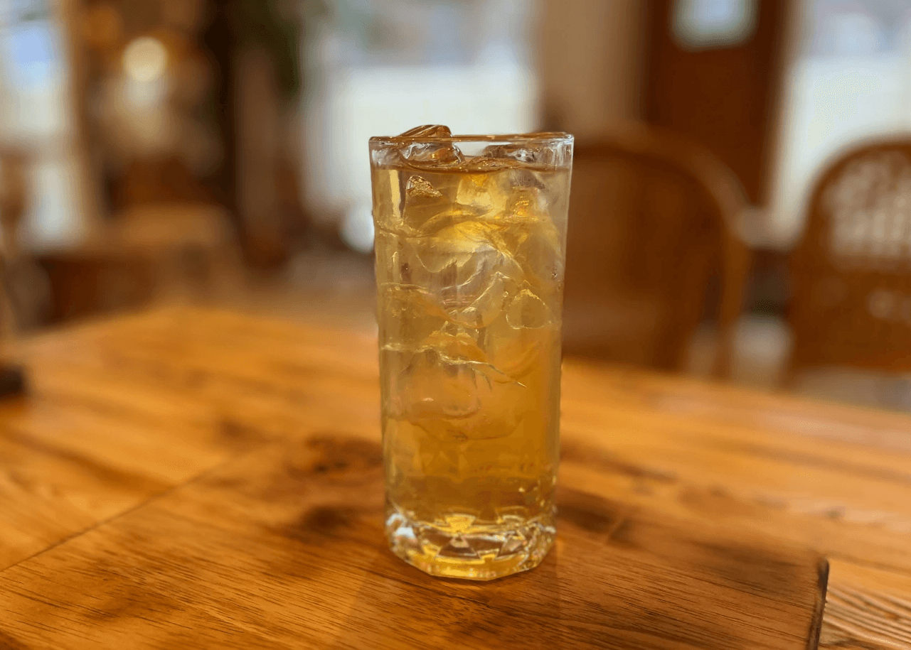 a glass of cocktail with a slime orange fruit