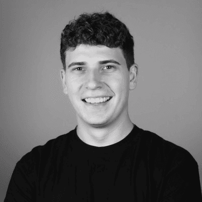A thoughtful young person with dark hair gazes to the side, captured in soft black and white lighting.