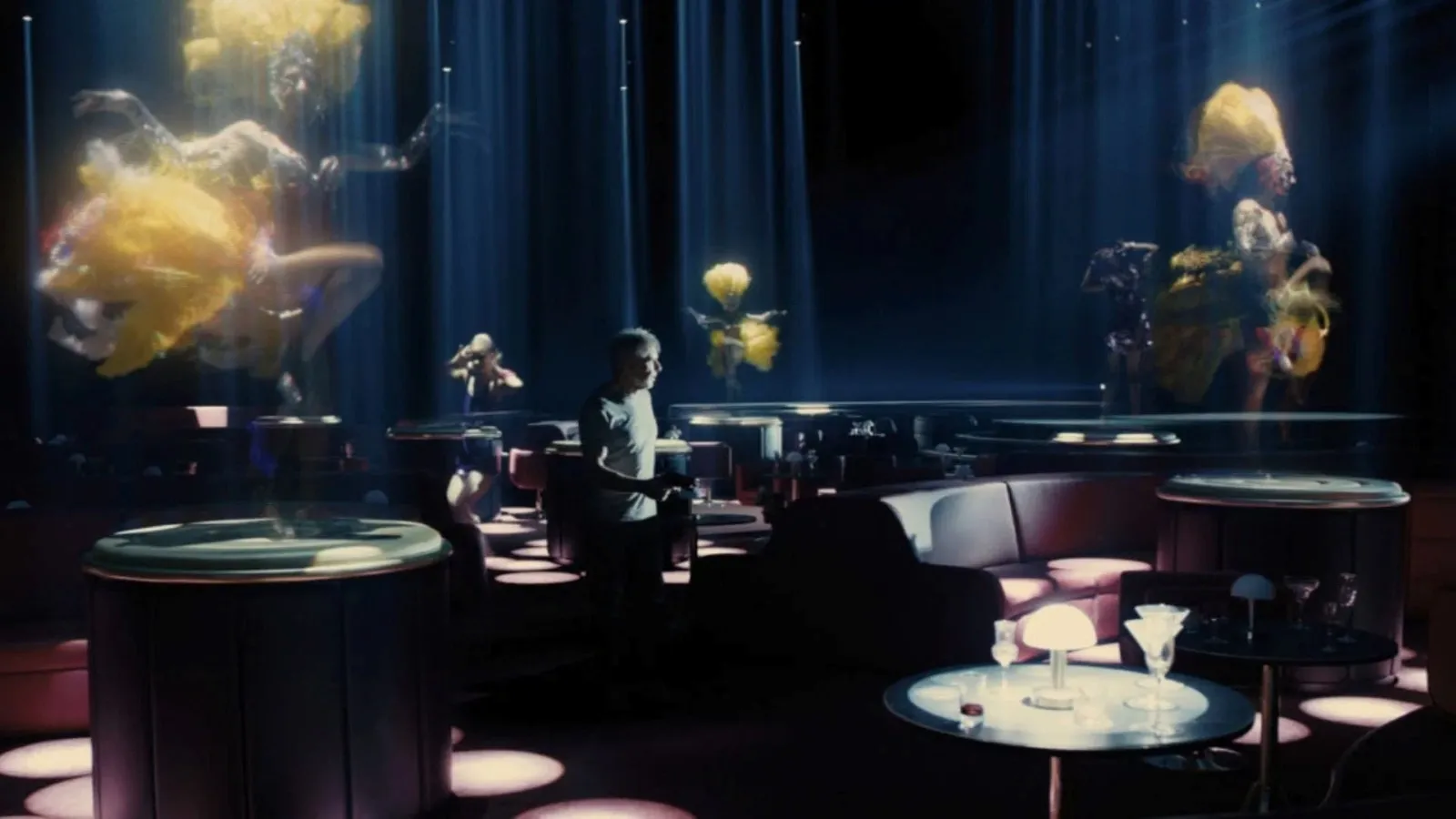A dimly lit, futuristic bar room features a lone figure wondering amidst scattered round tables, with ethereal holographic dancers hovering in mid-air, casting vibrant yellow light throughout the space.