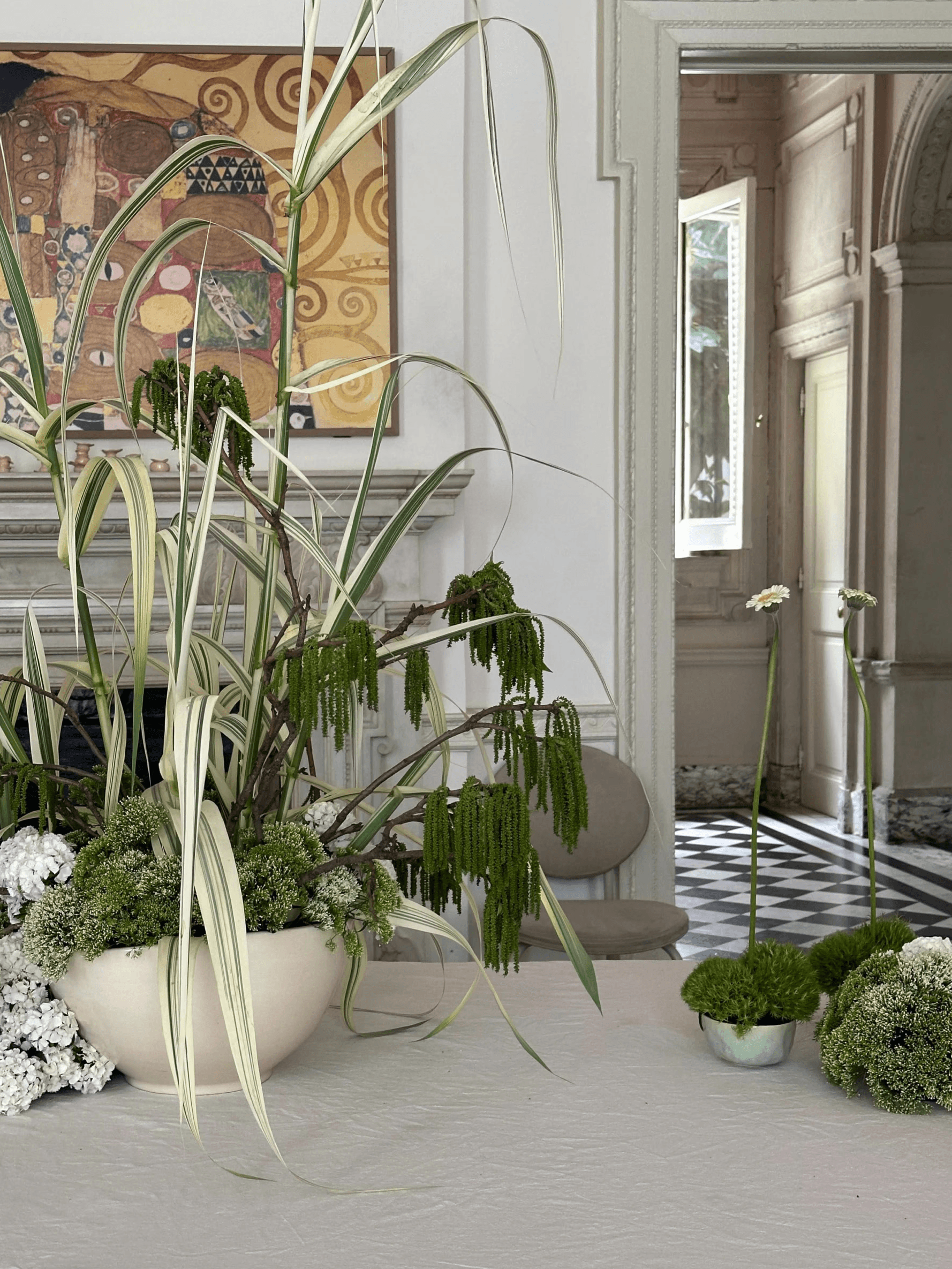 Arreglo floral contemporáneo en tonos verdes y blancos en interior clásico, con estética artística y natural.