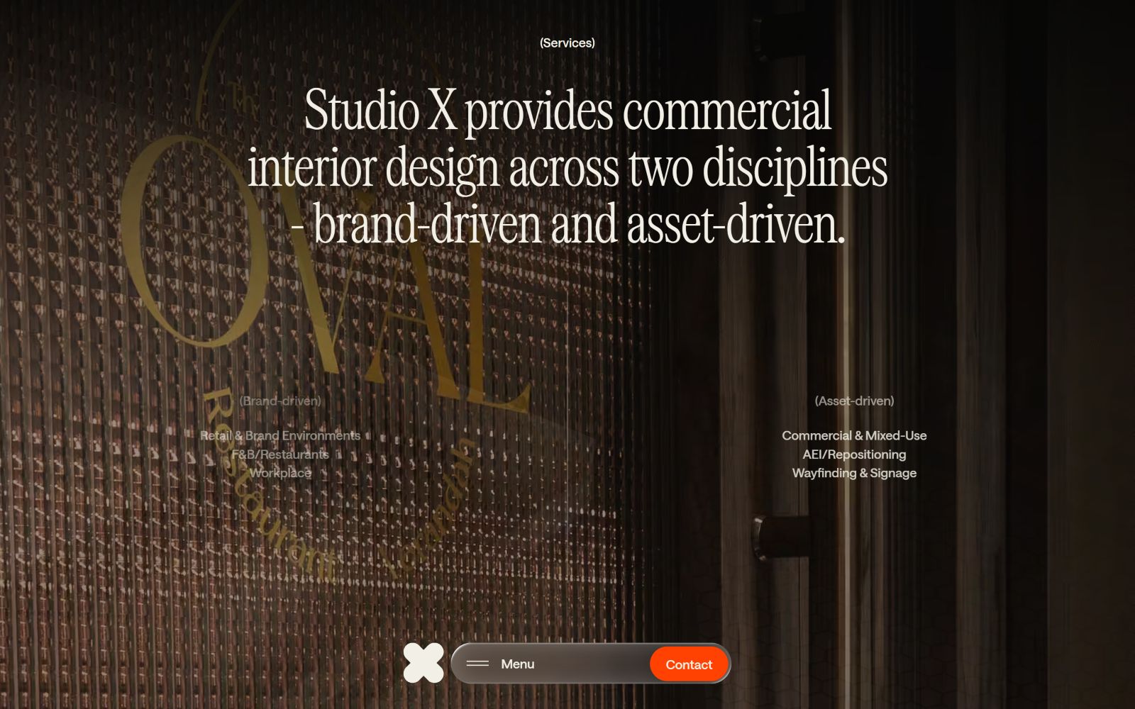 Dimly lit textured wall with "OVAL" and "Services" visible. Text: "Studio X provides commercial interior design..." with orange "Contact"...