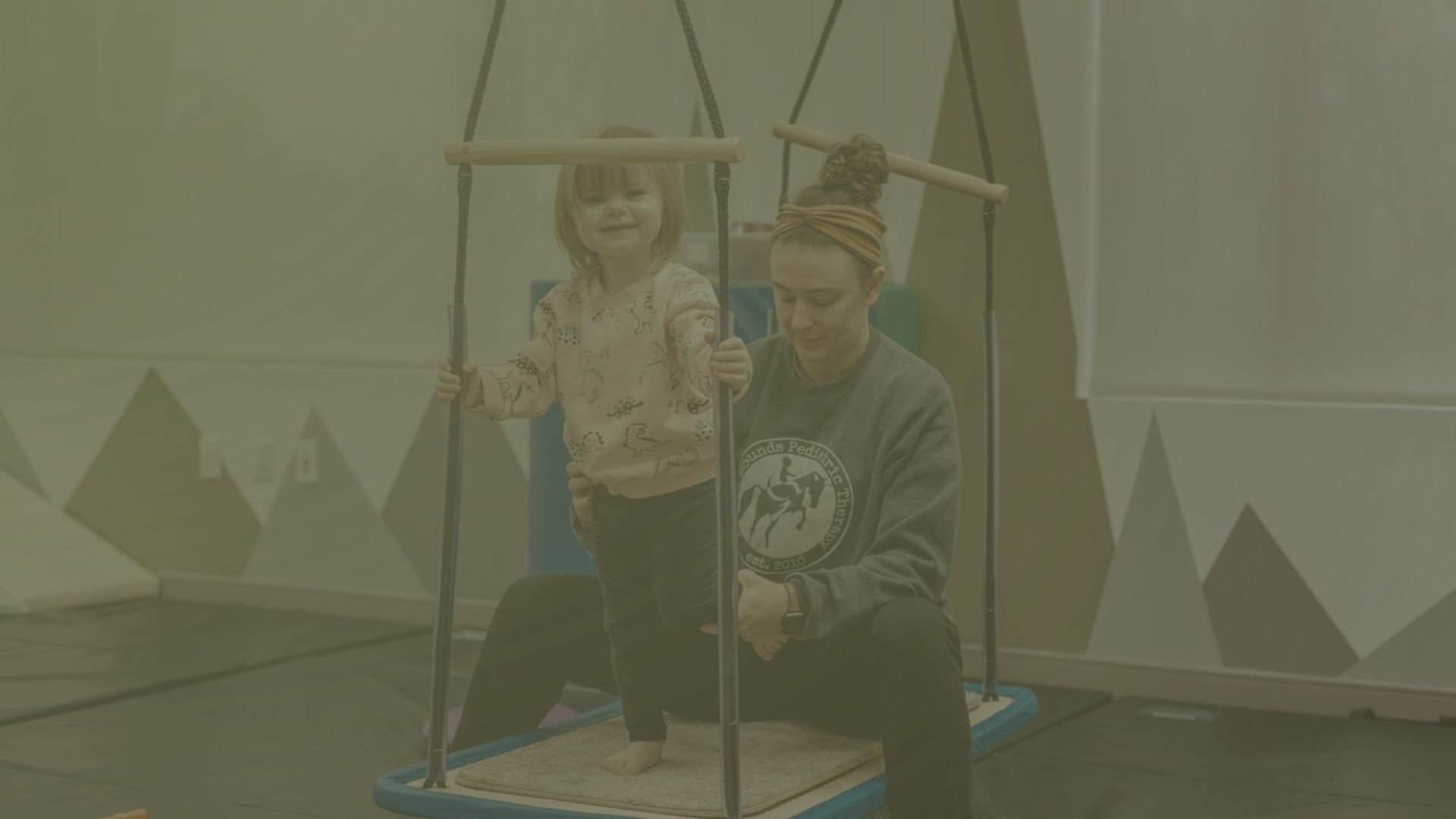 Child on swing with therapist at Leaps & Bounds Pediatric Therapy.