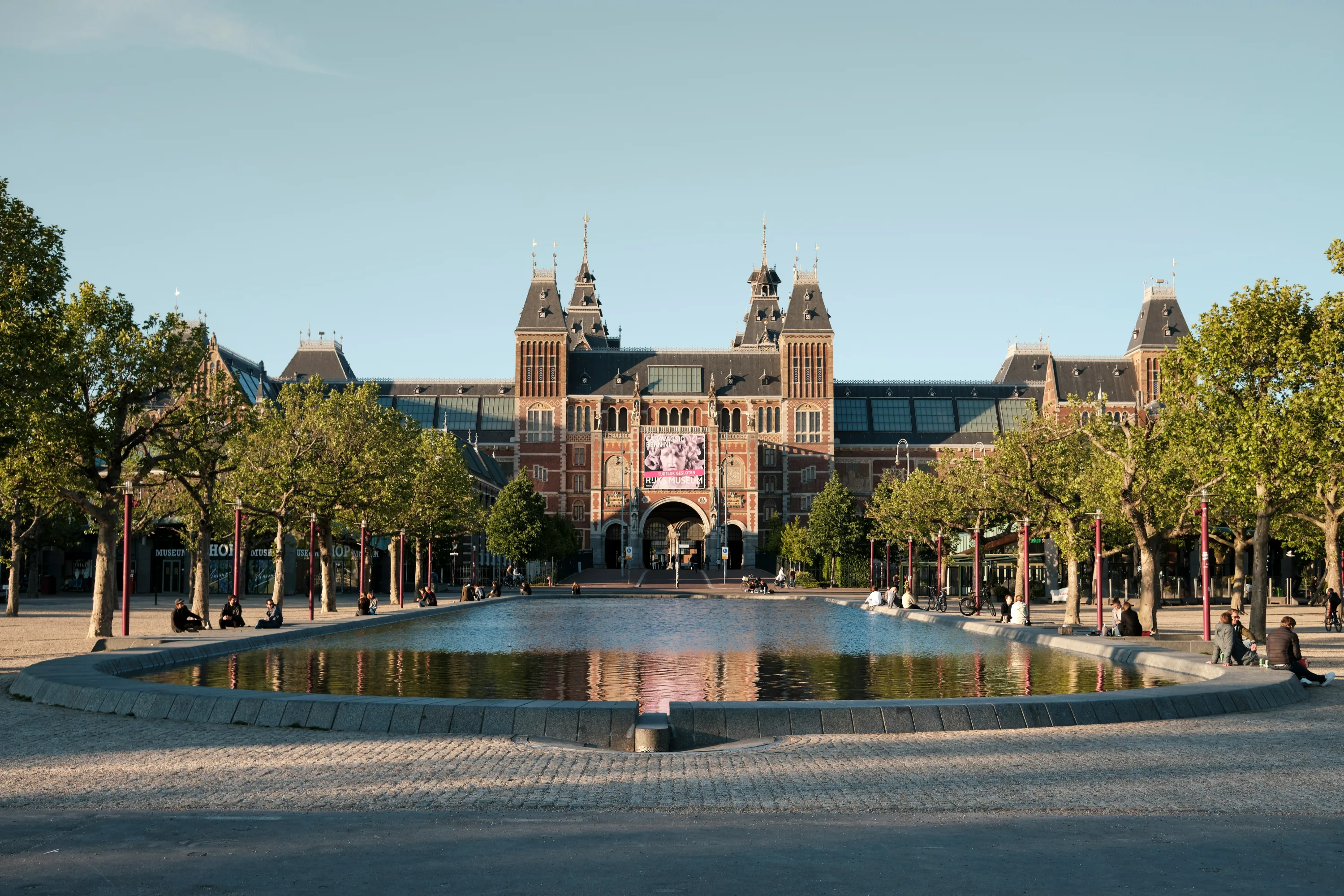 Rijksmuseum Amsterdam, iconic Dutch museum with a grand facade, reflecting pool, and manicured trees.