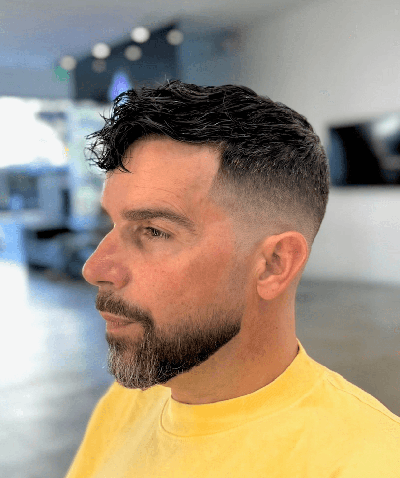 Thick beard grooming paired with a clean drop fade, ideal for a modern yet classic style by barber Courtney Palmore.