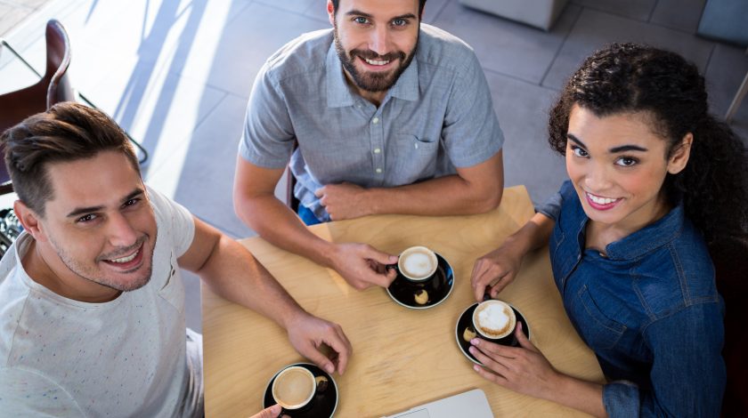 Portrait of smiling friends sitting a table and drinking a coffe