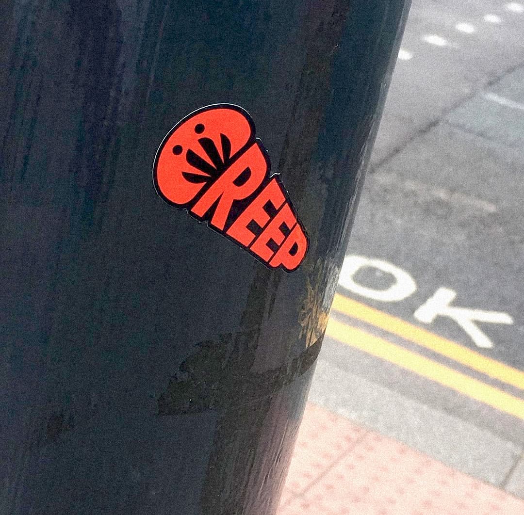 creep sticker in urban street on grey pole.