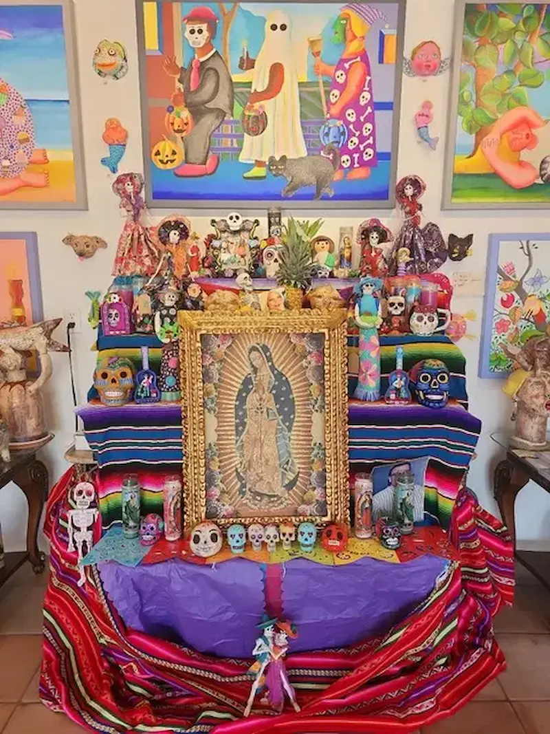 A vibrant Día de los Muertos altar at the Village of the Arts in Bradenton, FL, adorned with colorful skull ornaments, traditional cloths, and artwork, showcasing Mexican cultural heritage.