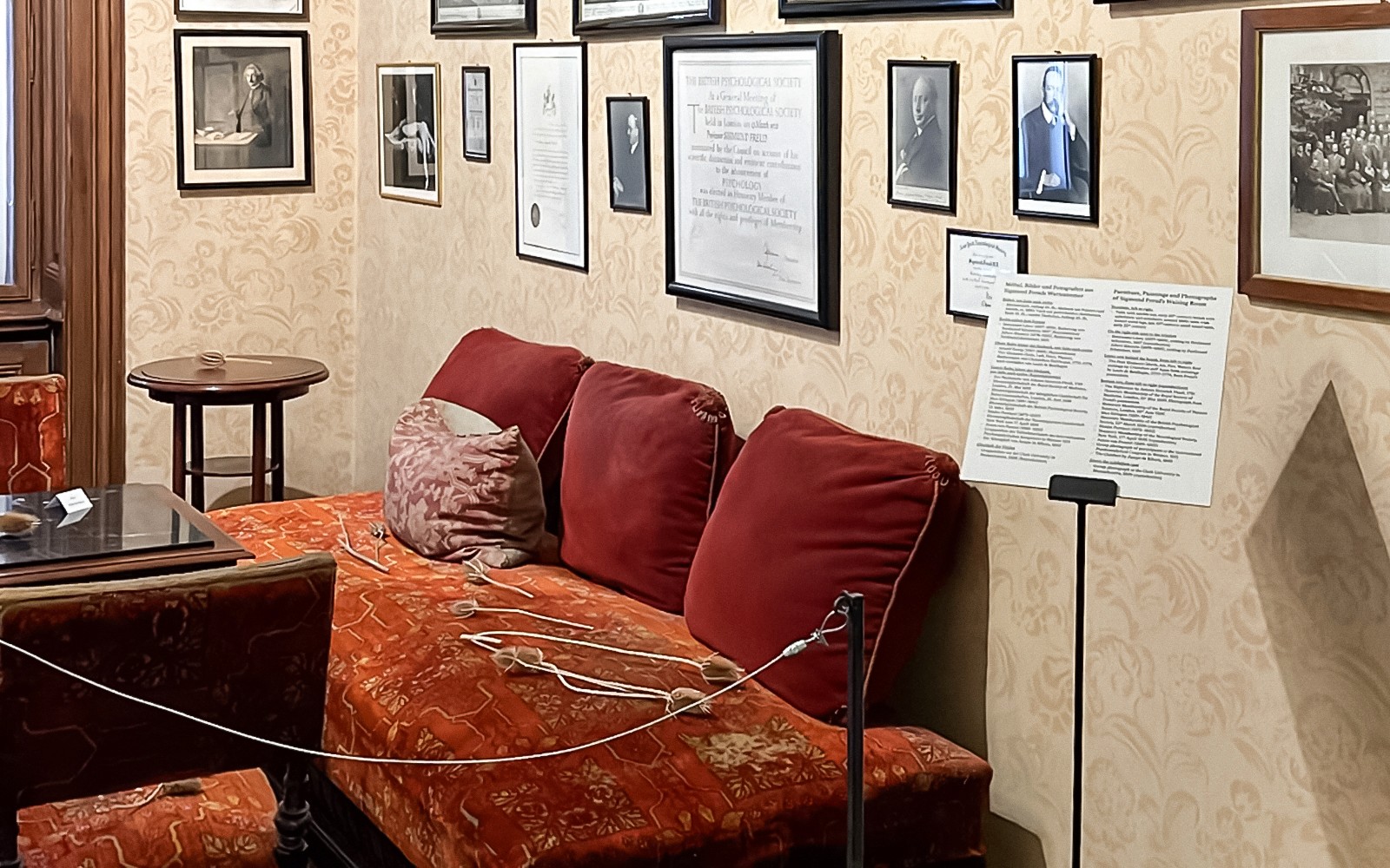Interior Museum Sigmund Freud dengan sofa merah dan foto berbingkai di dinding.