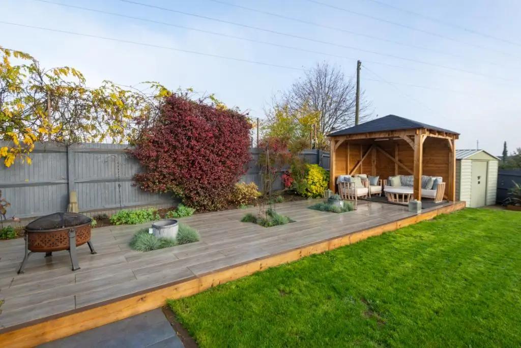 A landscaped backyard featuring a patio, plants, and a gazebo under a clear sky.