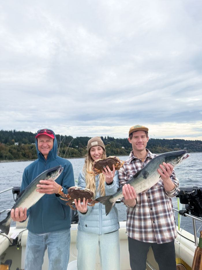 Three guest holding Coho Salmon and Dugeness Crab t a seattle fishing charter boat