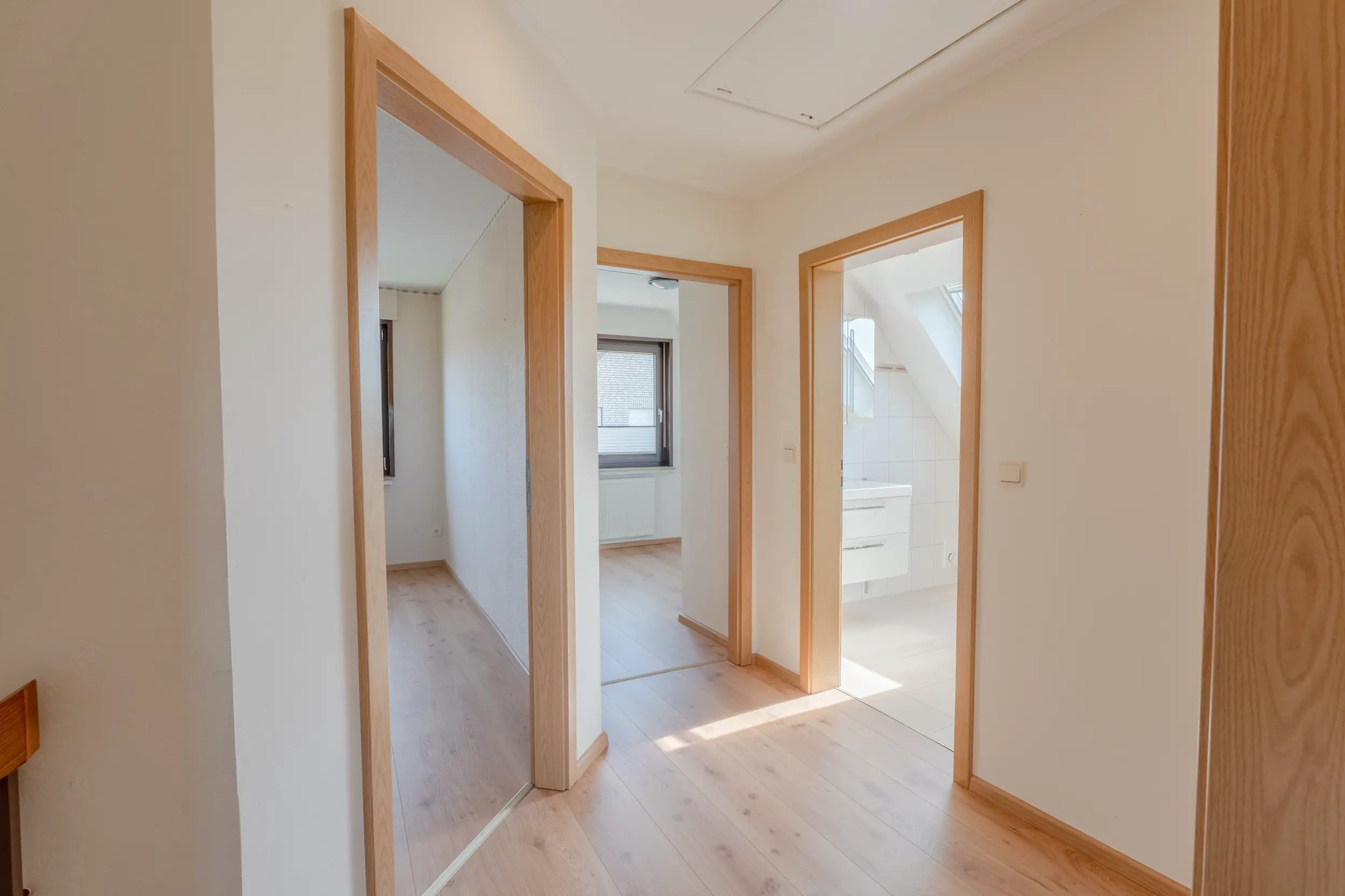 Heller Flur im Obergeschoss mit Laminatboden und mehreren offenen Türen zu den angrenzenden Räumen.