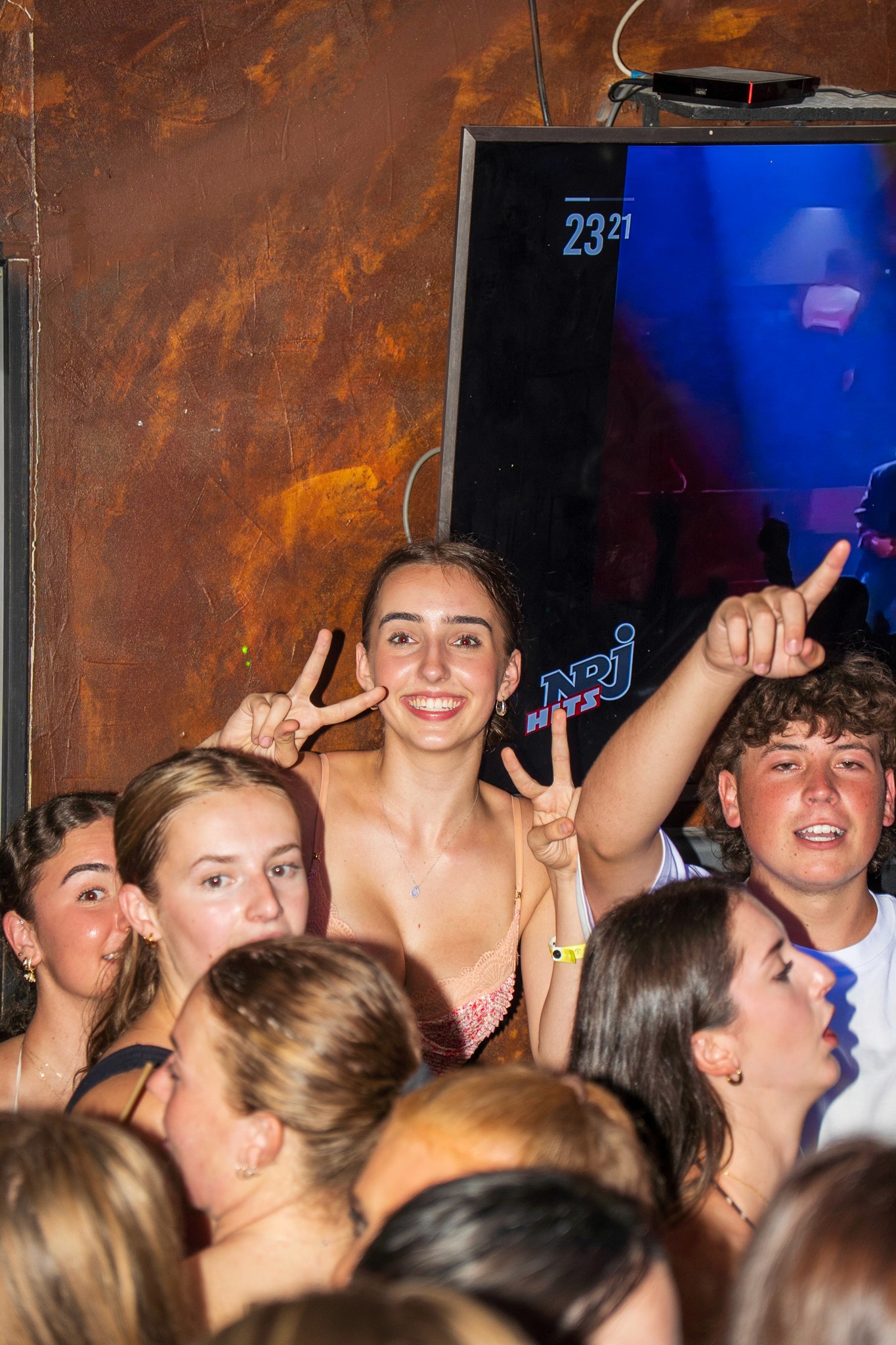 A lively group of international travelers enjoying nightlife together in Nice, walking between bars with music and warm city lights around them.