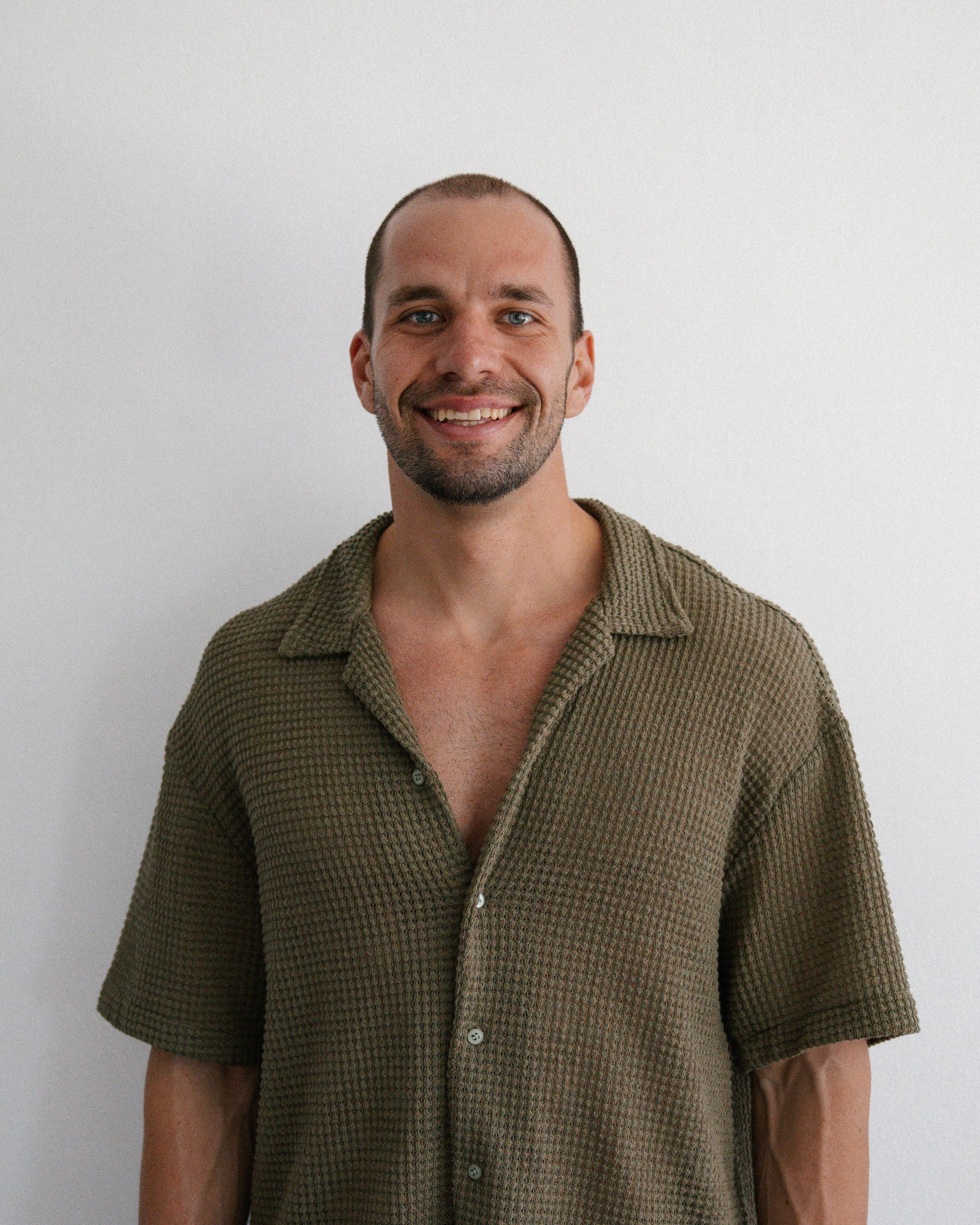 Mikaela, a SaunaHaüs facilitator, smiling in warm natural light with a soft background.