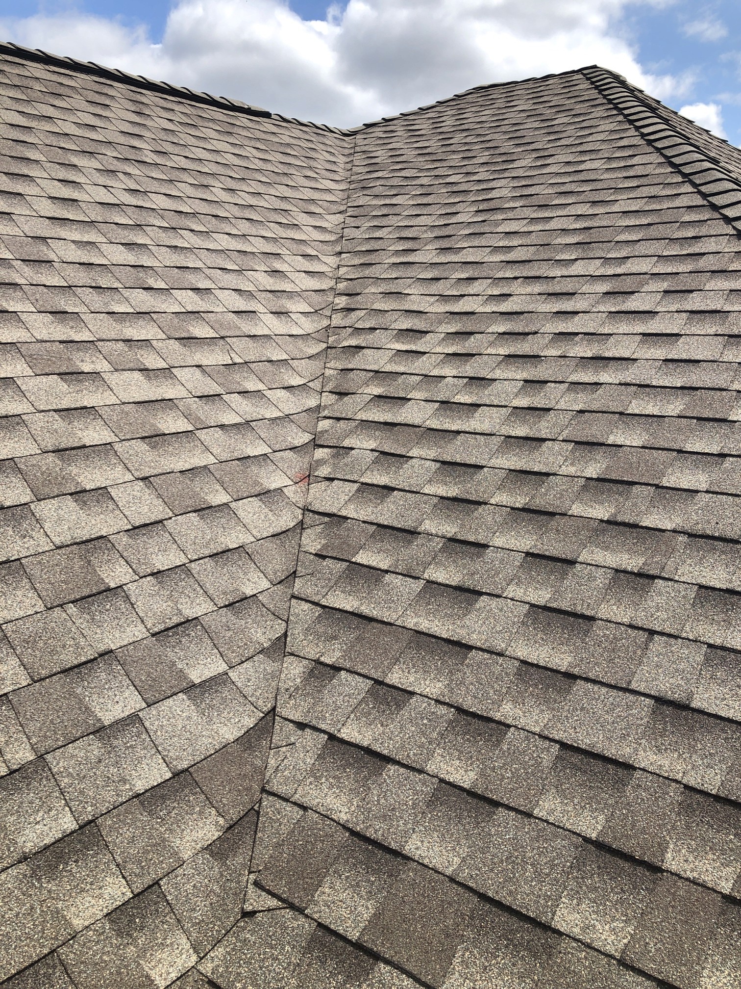 Close-up of dimensional asphalt shingles showing overlapping courses and contrasting granules; manufacturer not verified.