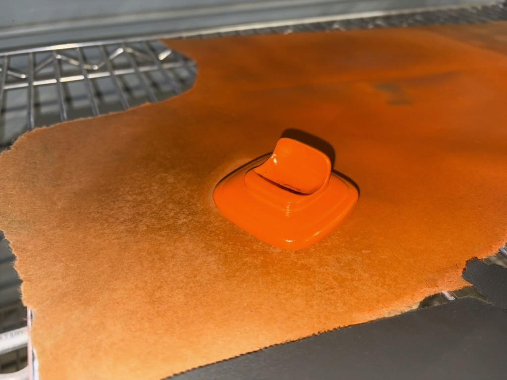 oscar's orange belly piece drying on the same rack after being spray-painted