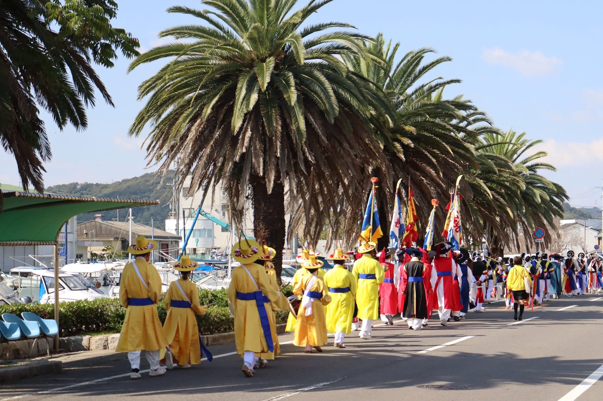 A group of performers walking down the street wearing traditional Korean clothing