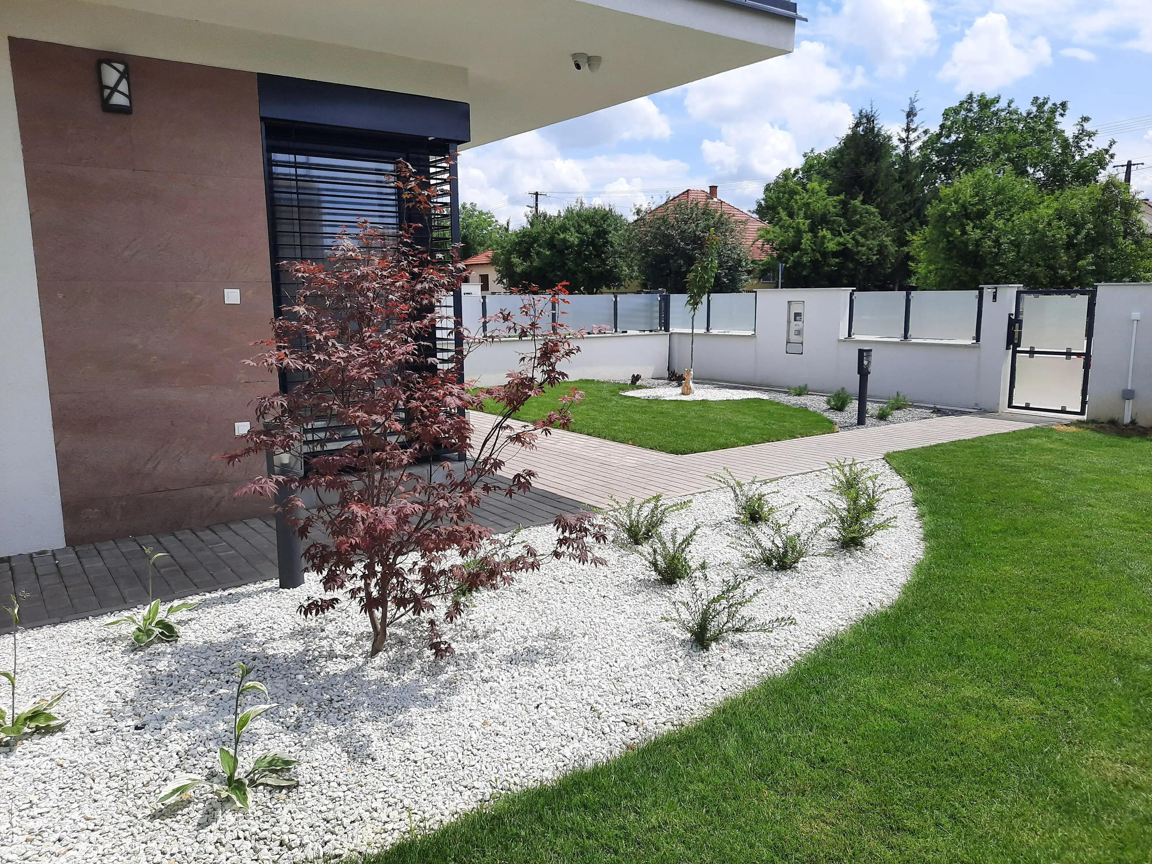 Szintkülönbségű kertépítés kőlépcsőkkel és gyepfelülettel