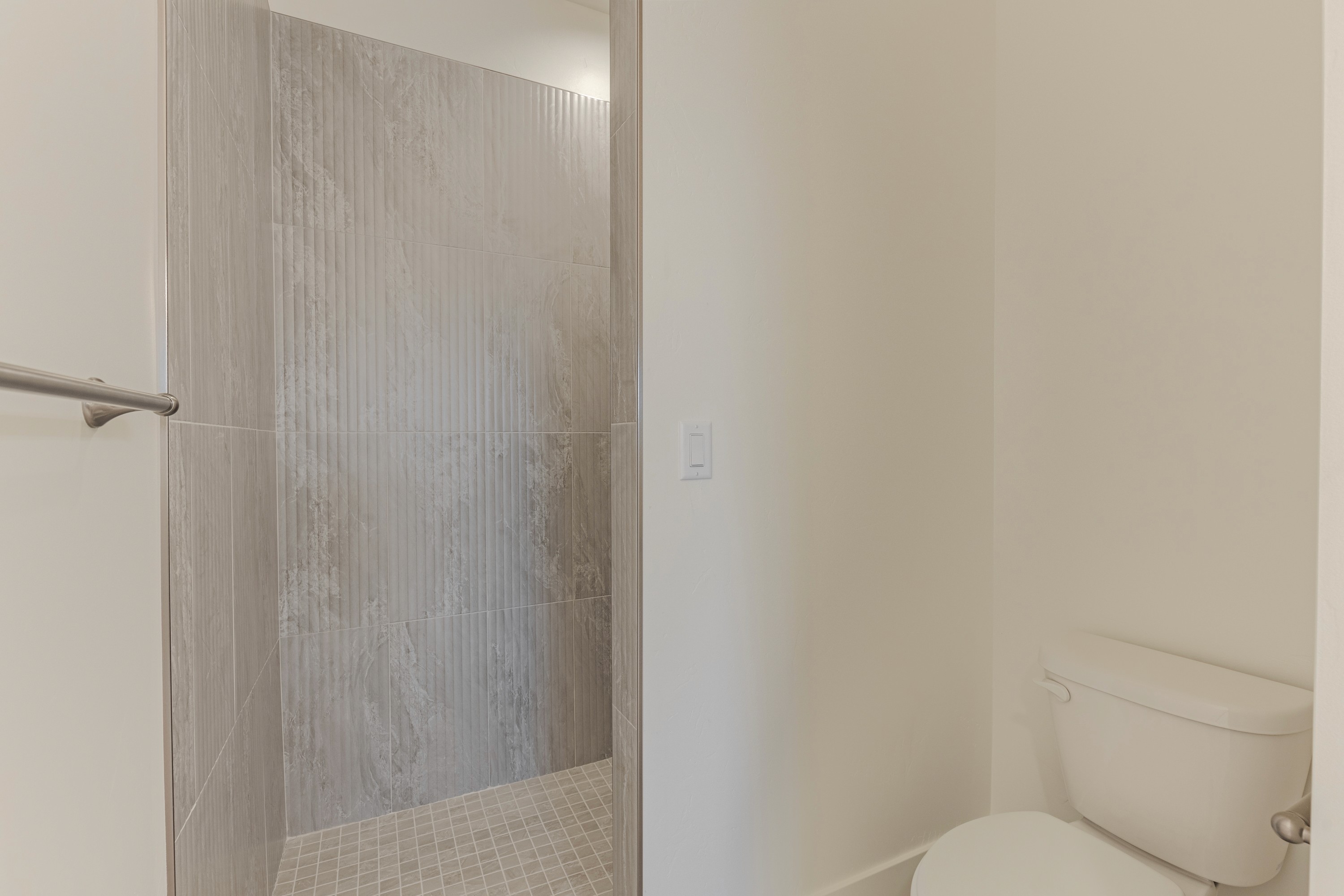 Master bathroom walk-in shower in the Painted Sands twin home in Hurricane, Utah with clean tile finishes.
