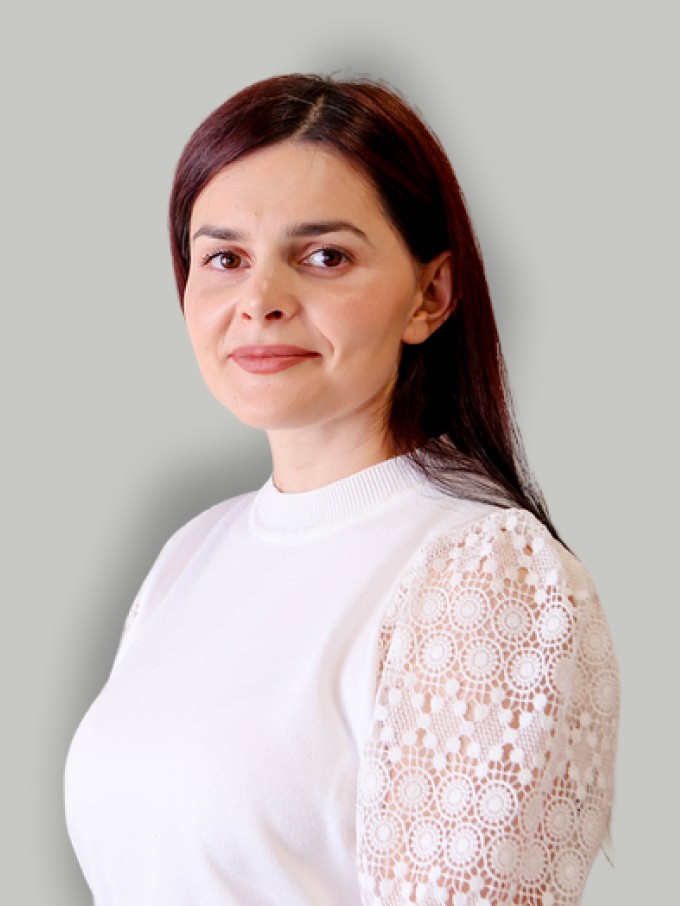 A woman with straight blonde hair wearing a light colored sweater looks away.