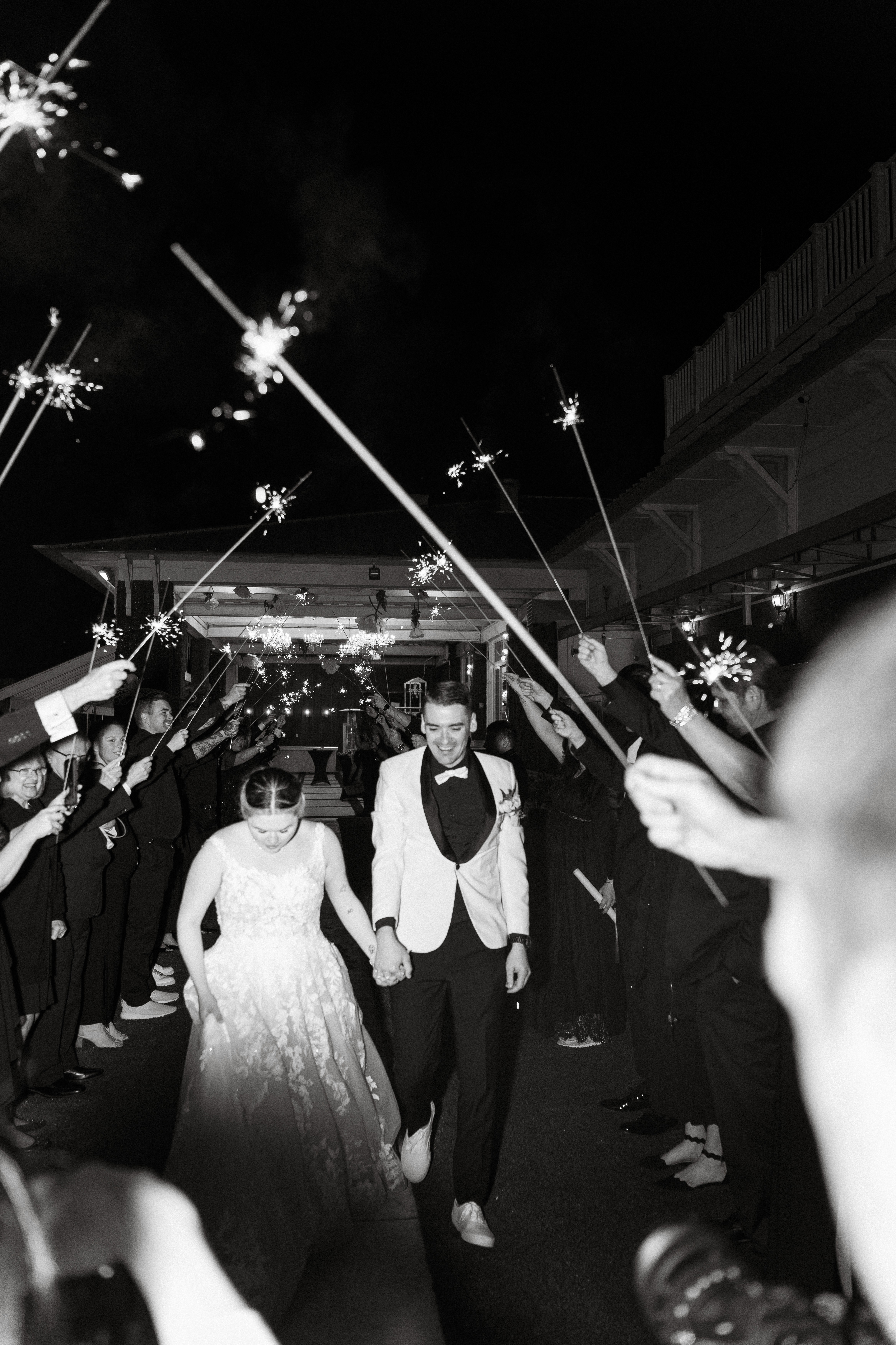 A couple in wedding attire shares a romantic kiss on a leafy path by a tranquil river.