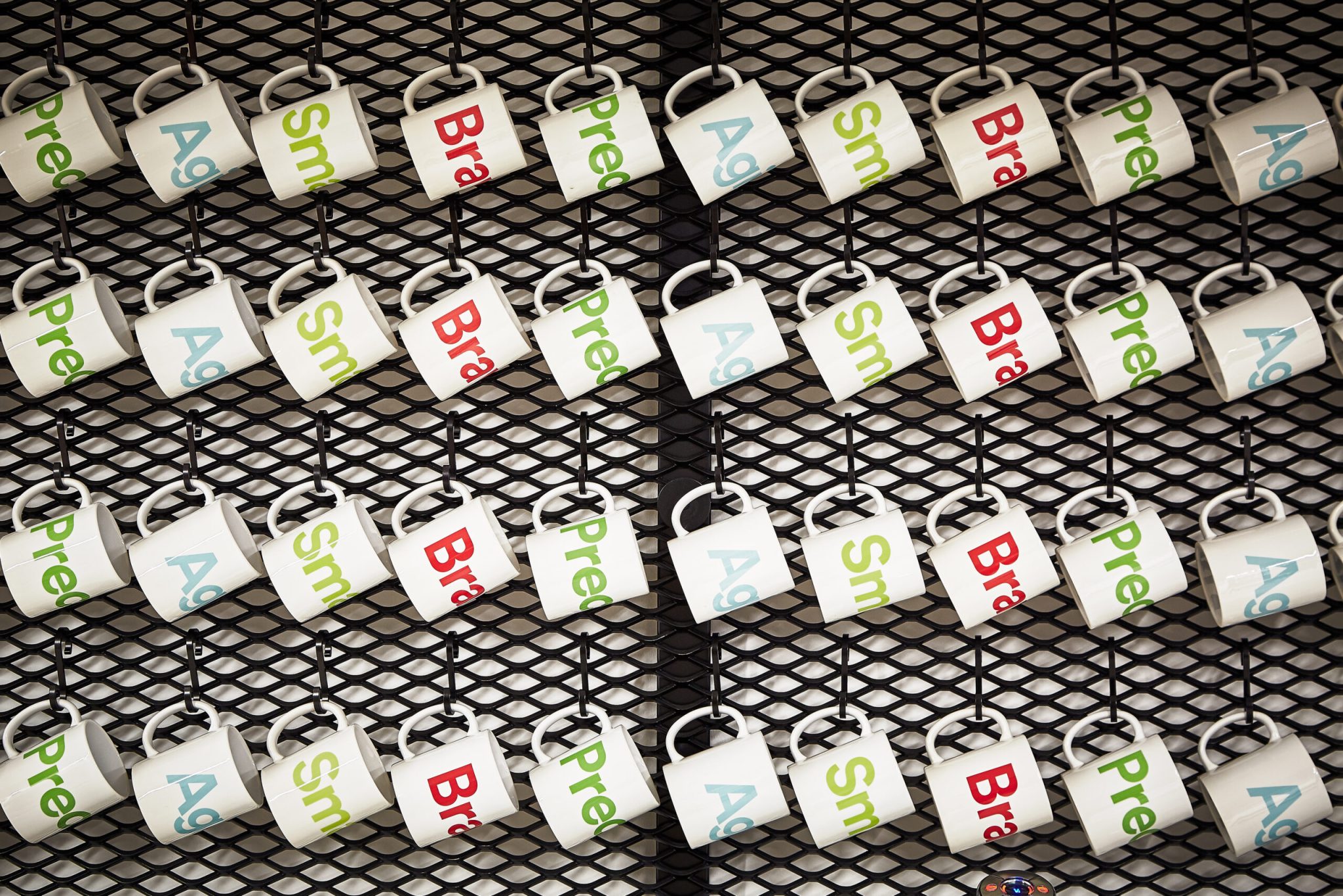 Wall display of branded mugs hanging in rows