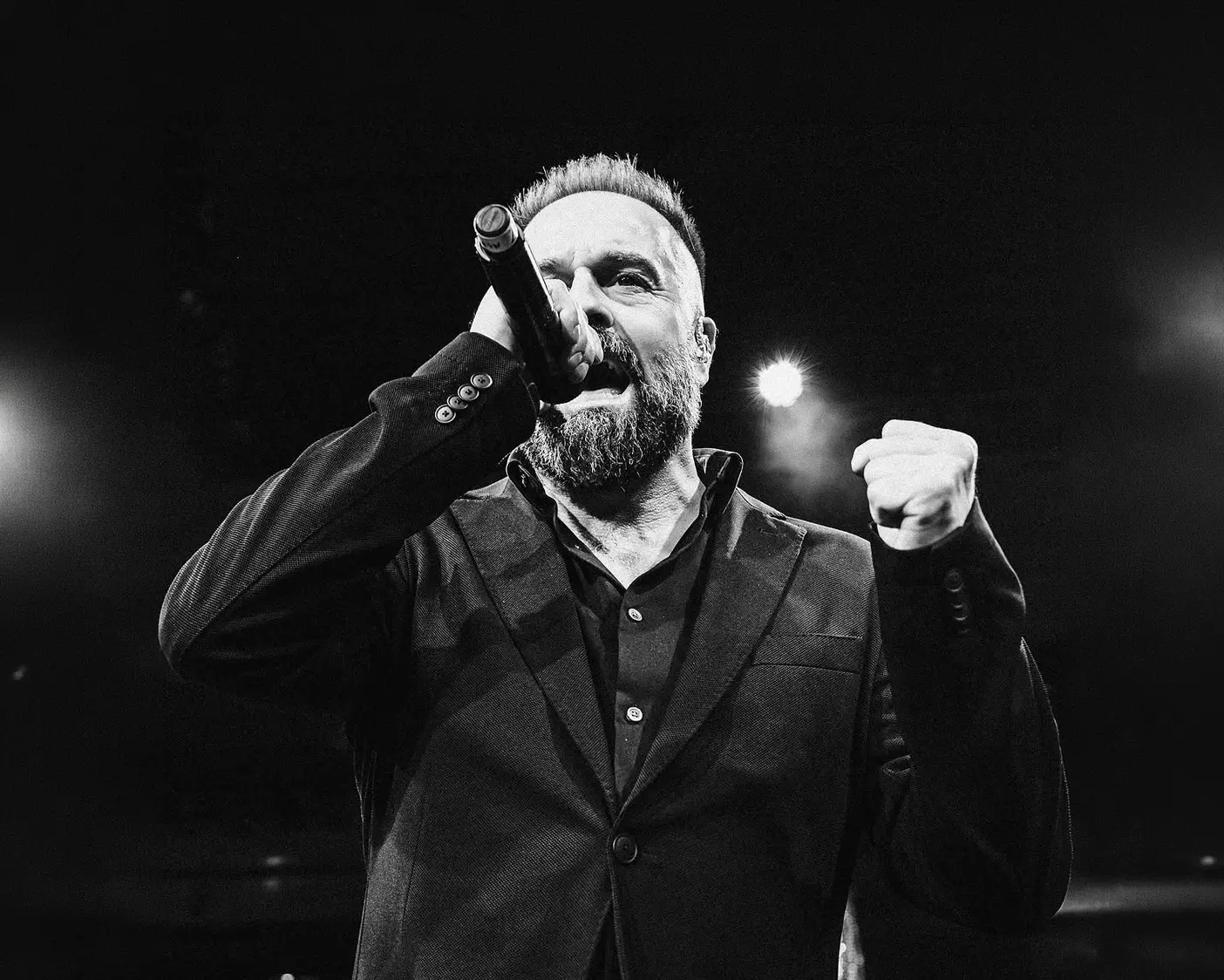 Man singing into a microphone, fist raised.