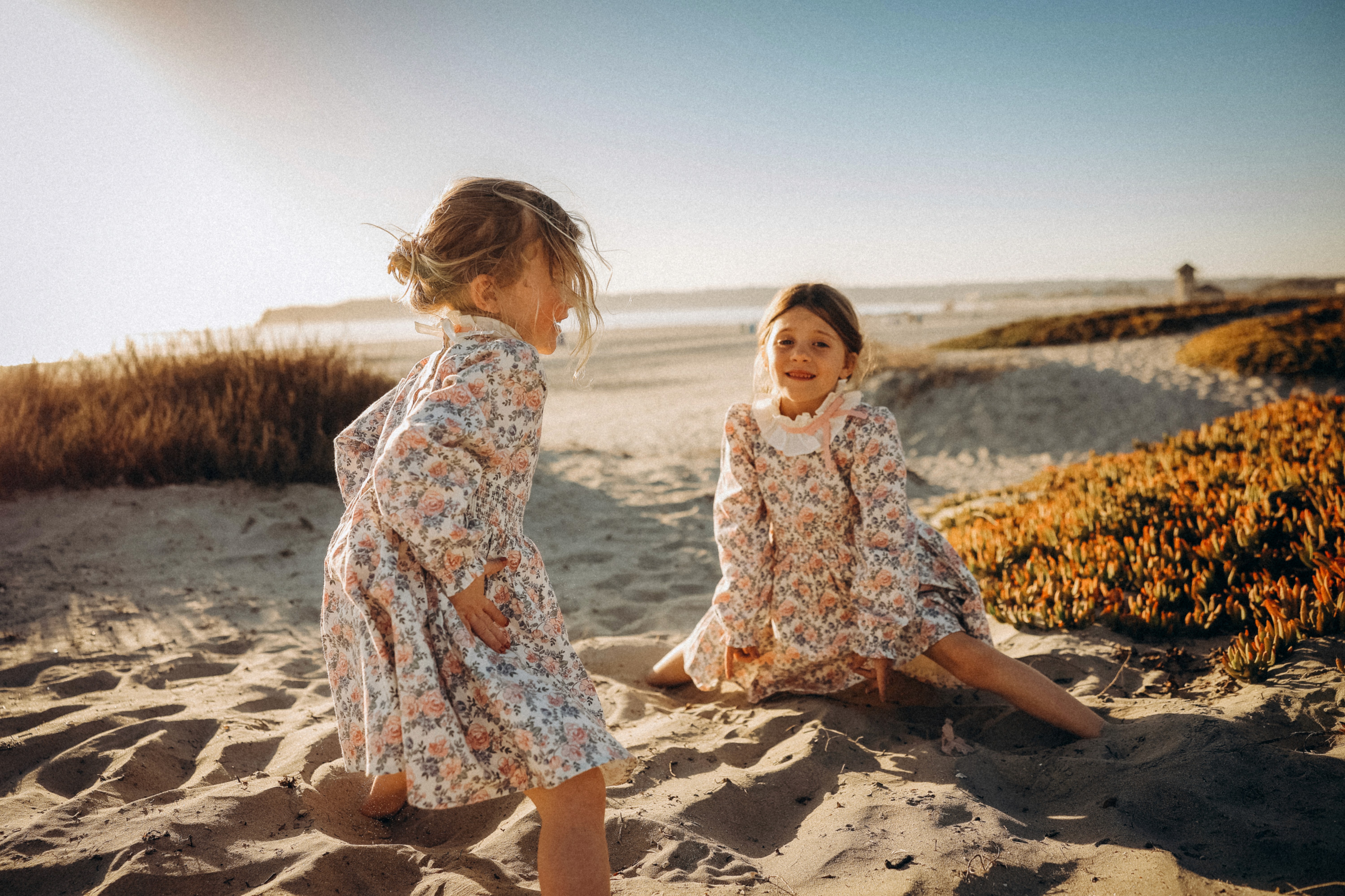 Kids running and playing together in the golden dunes at sunset.