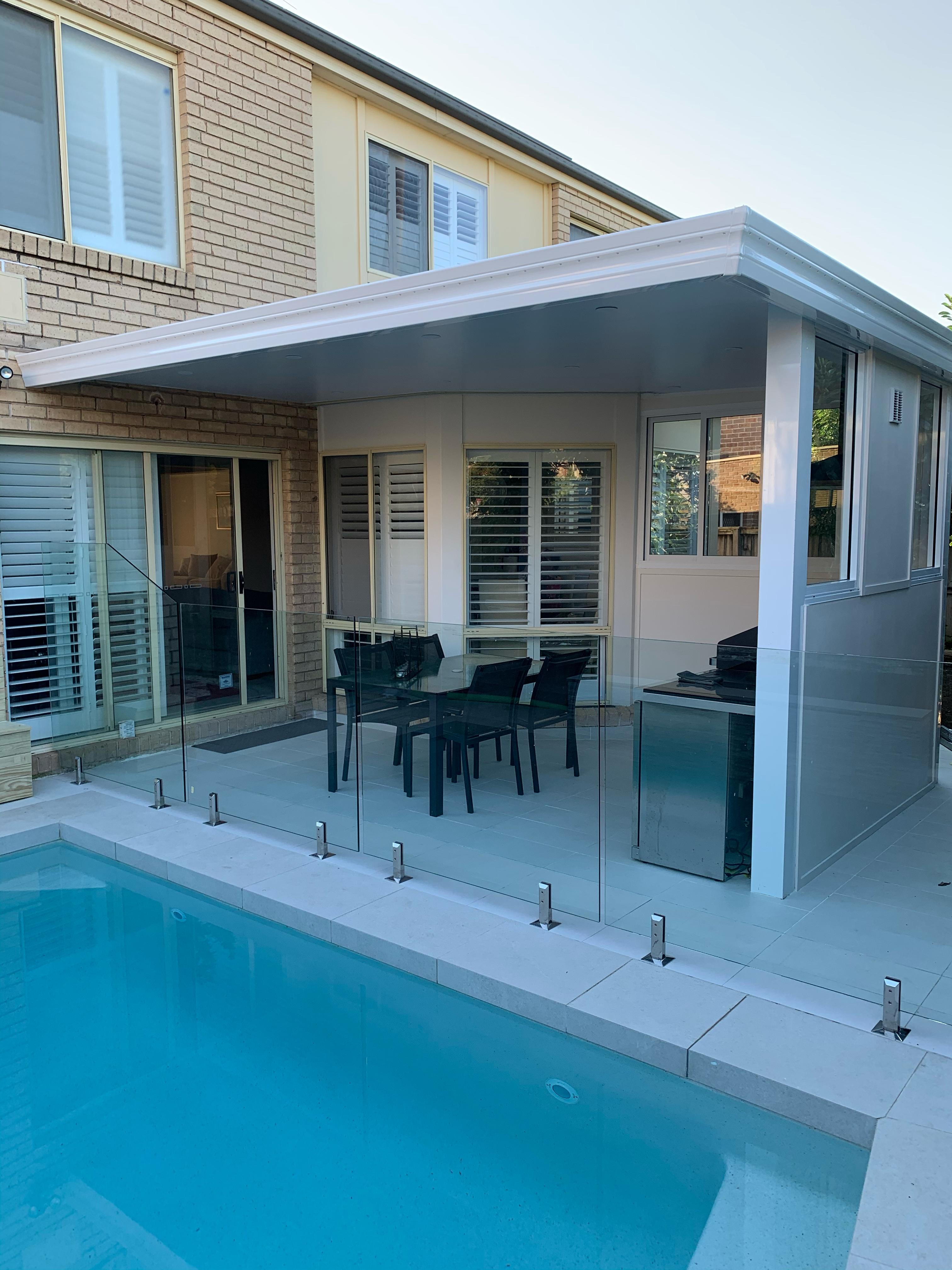 Modern outdoor pergola with enclosed pergola by the pool, featuring glass fencing, dining area, and durable low-maintenance design
