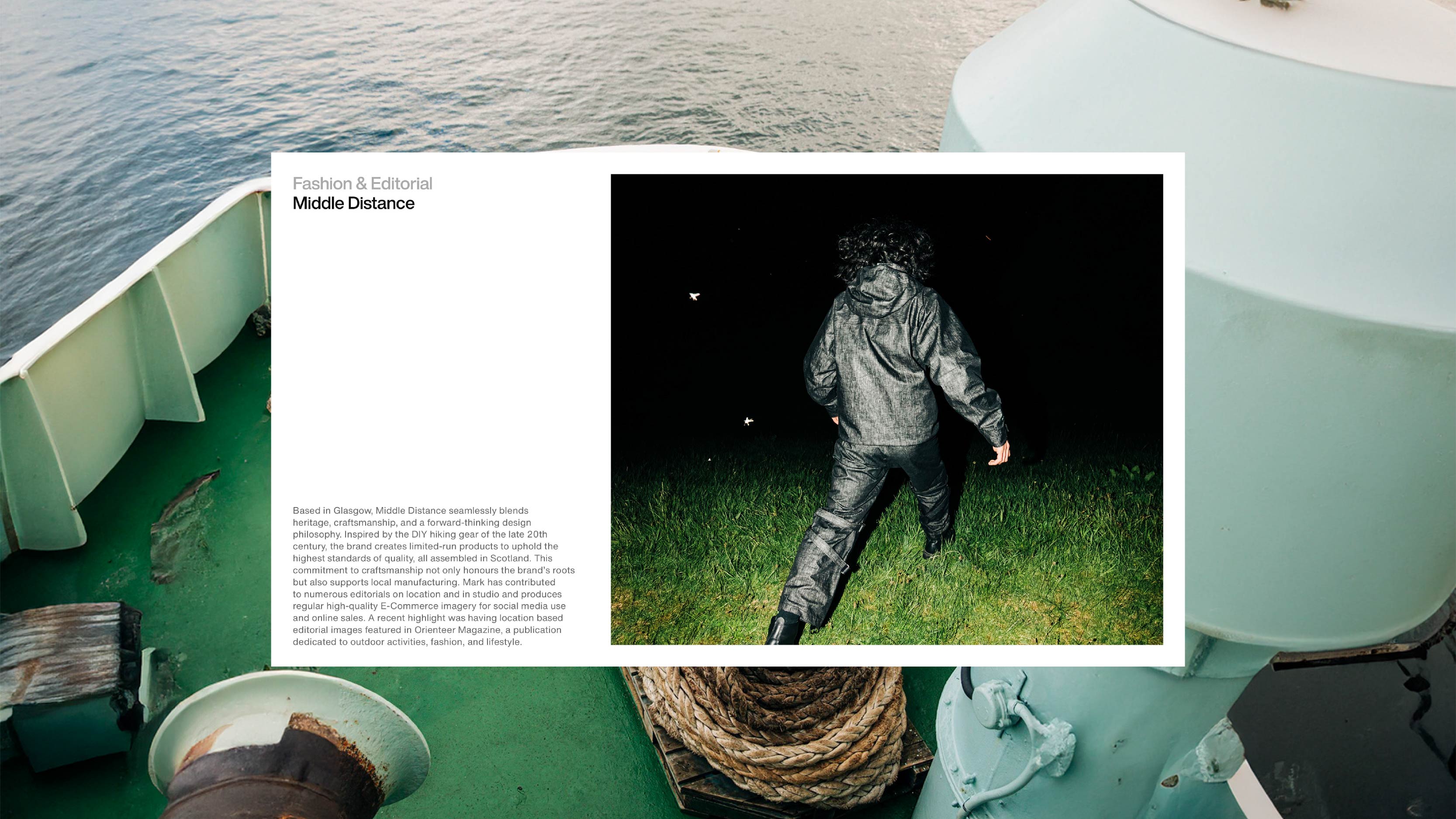 Modern minimalist desk setup with a computer monitor, microphone arm, camera, and indoor plants, featuring a pegboard with accessories on the wall and a Bauhaus-style poster leaning against the wall.