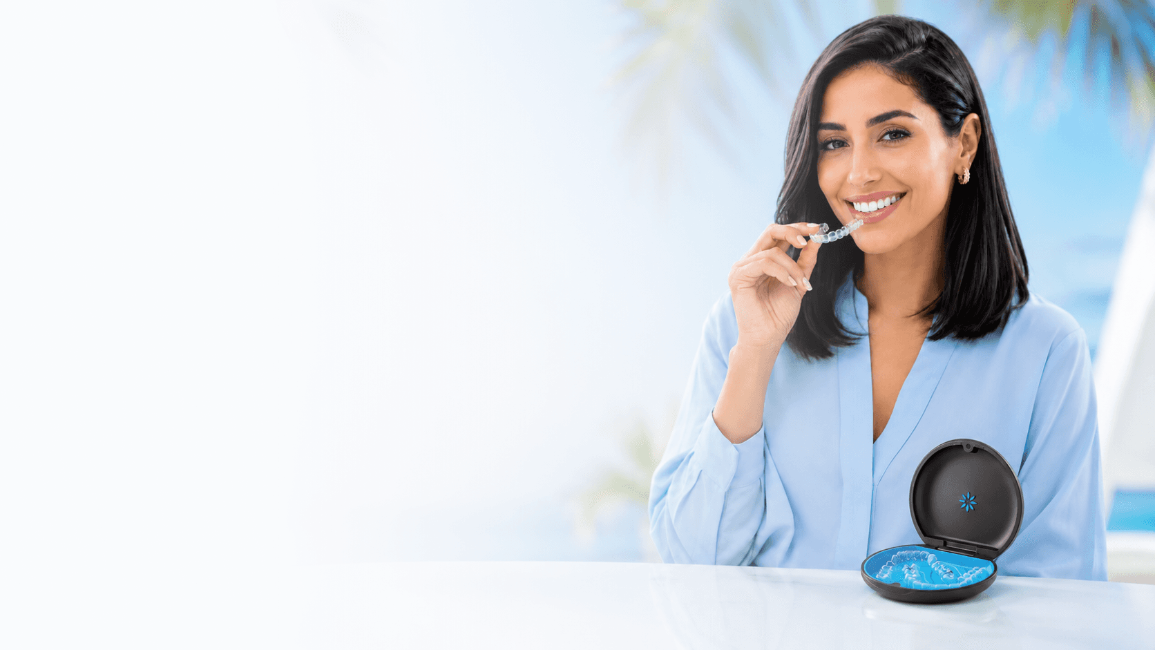 Smiling girl in blue shirt inserting Invisalign clear aligners, enjoy the summer offer now at Invisalign Center Dubai.